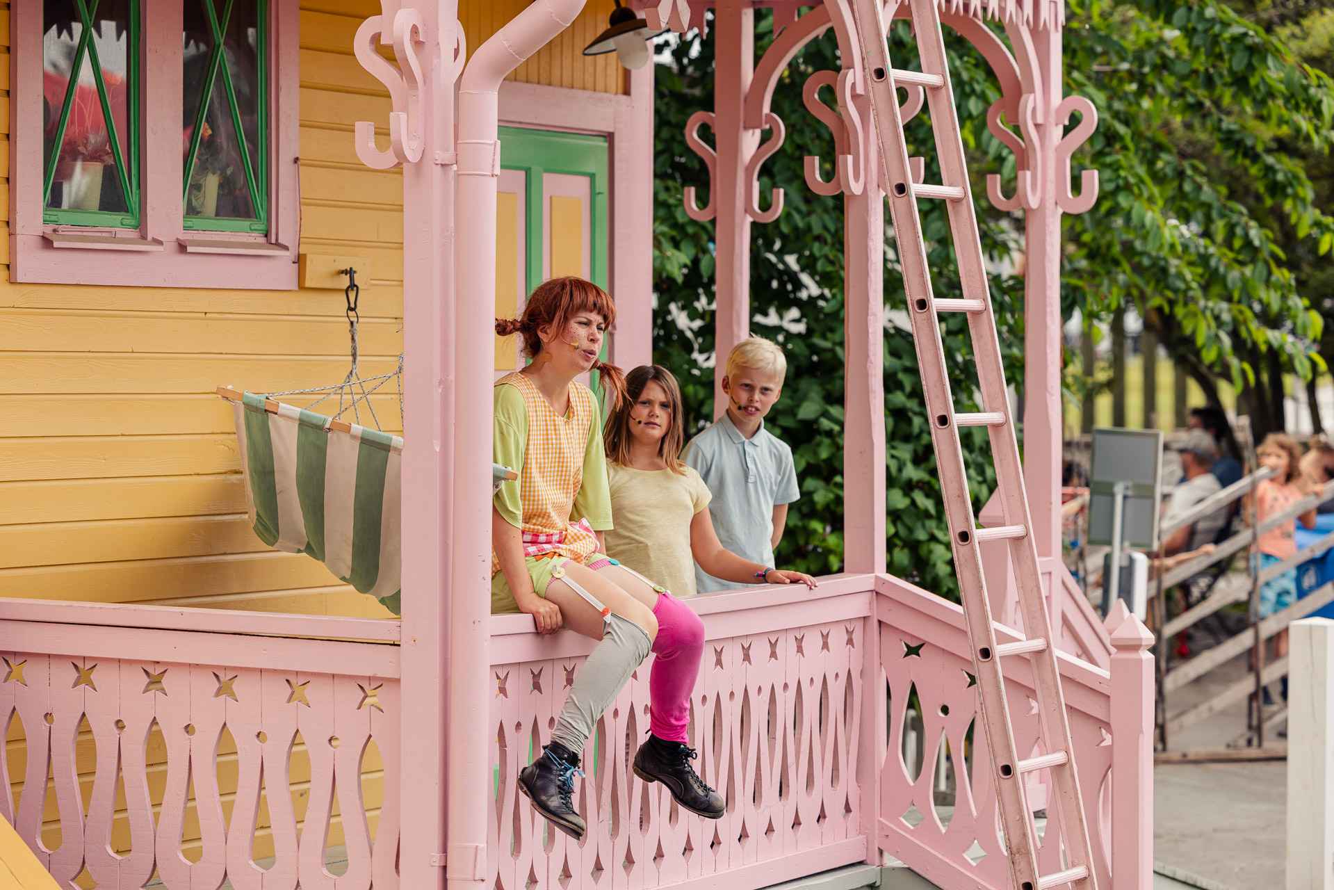 Une représentation théâtrale avec Fifi Brindacier qui est assise sous le porche de sa maison jaune avec Tommy et Annika à ses côtés.