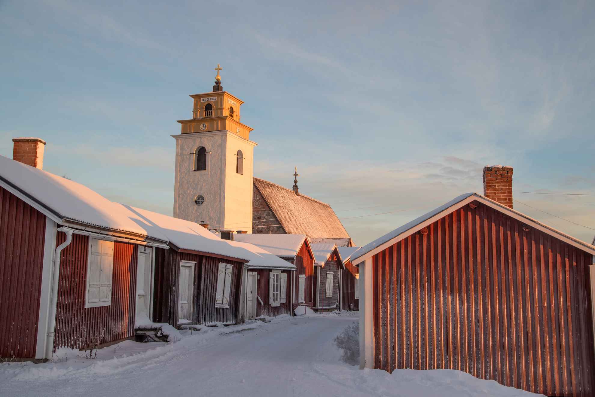 Red cottages and the white church tower in Gammelstad church town during winter.