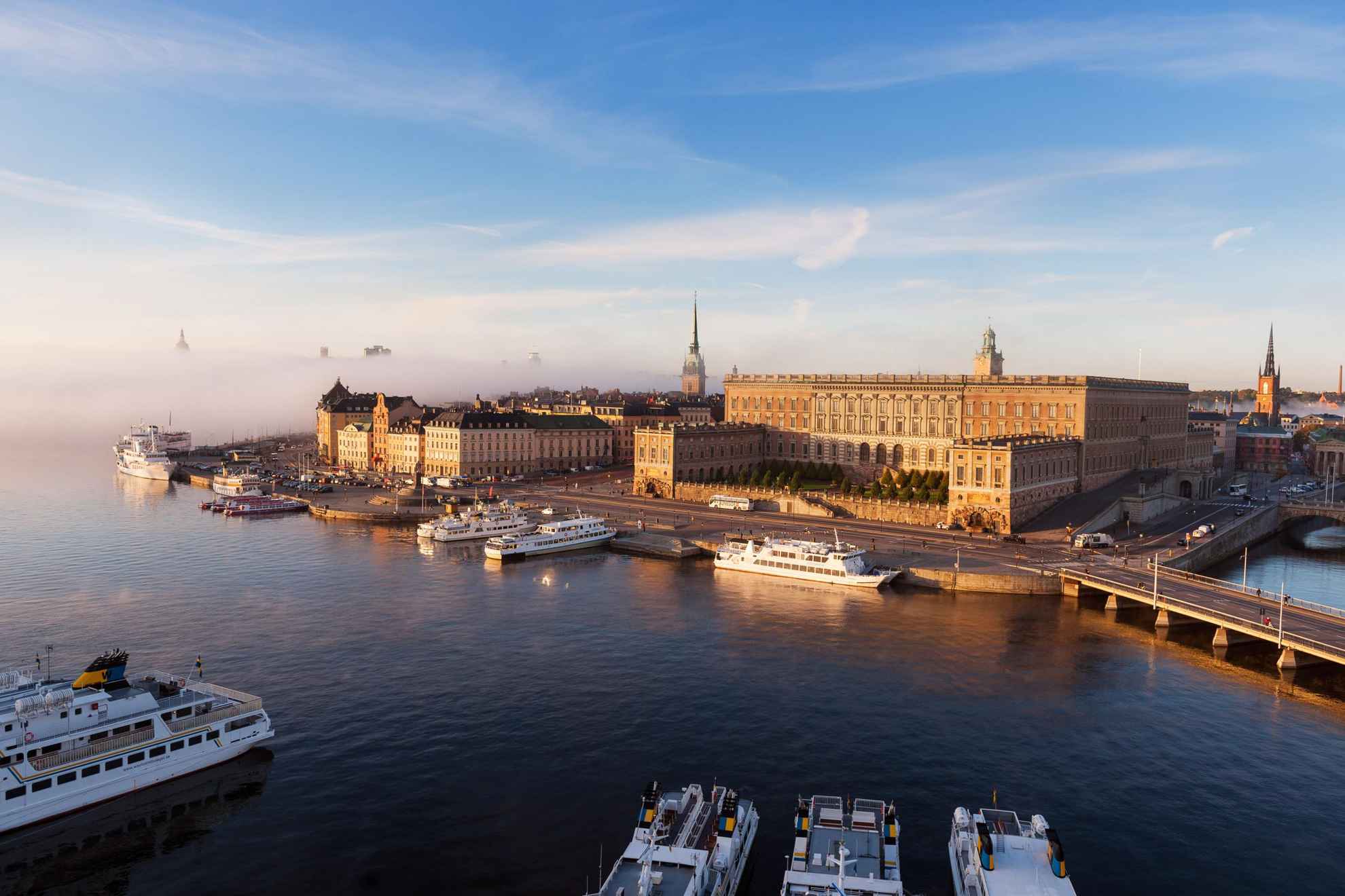 Vue aérienne du Palais royal de Stockholm et d'autres bâtiments de la capitale. Des bateaux sont amarrés le long des quais du port.