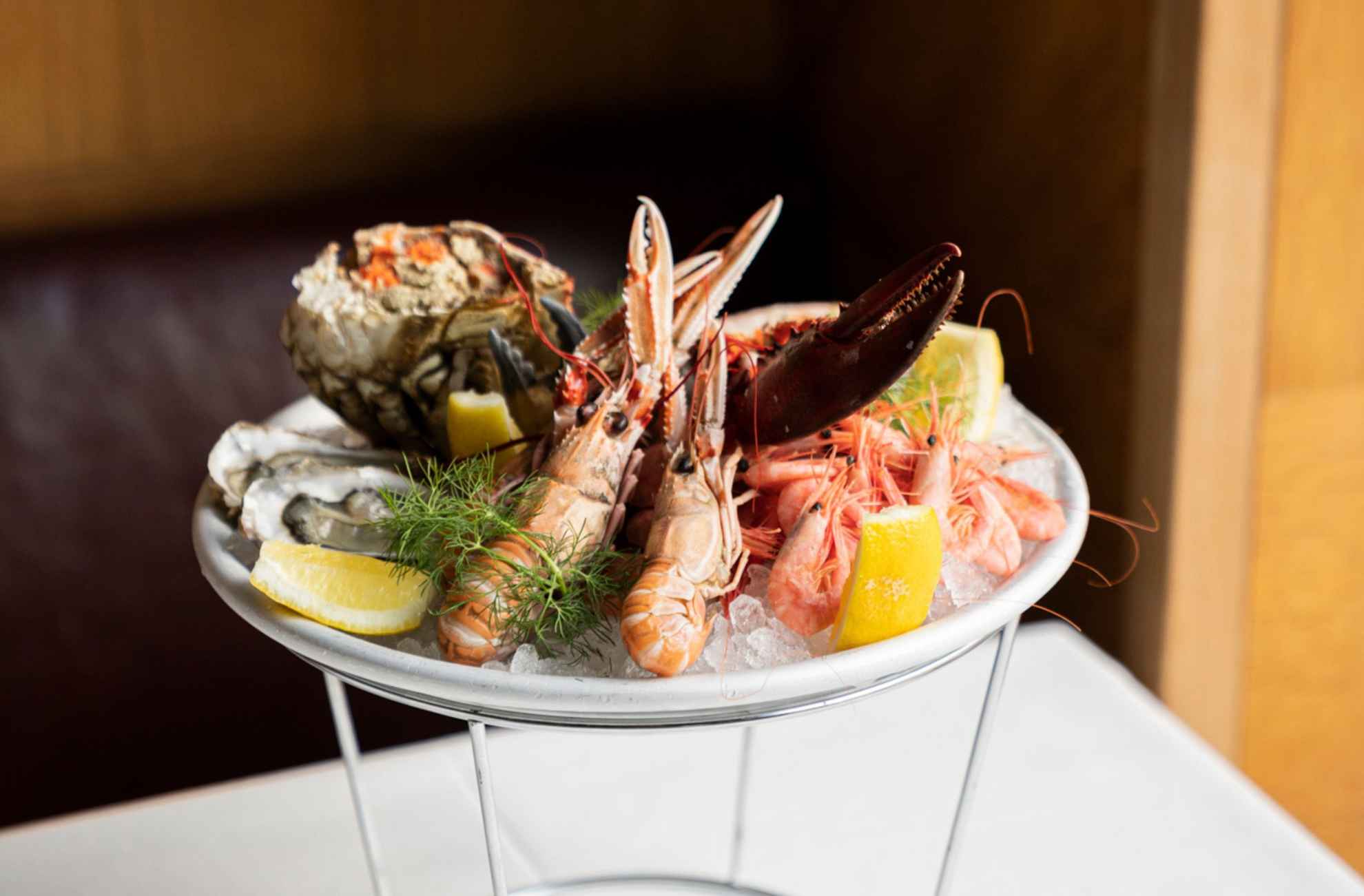 Des écrevisses, des huîtres, des crevettes, un crabe, du citron et de l'aneth frais sont disposés sur un plateau de fruits de mer, au restaurant Sturehof.