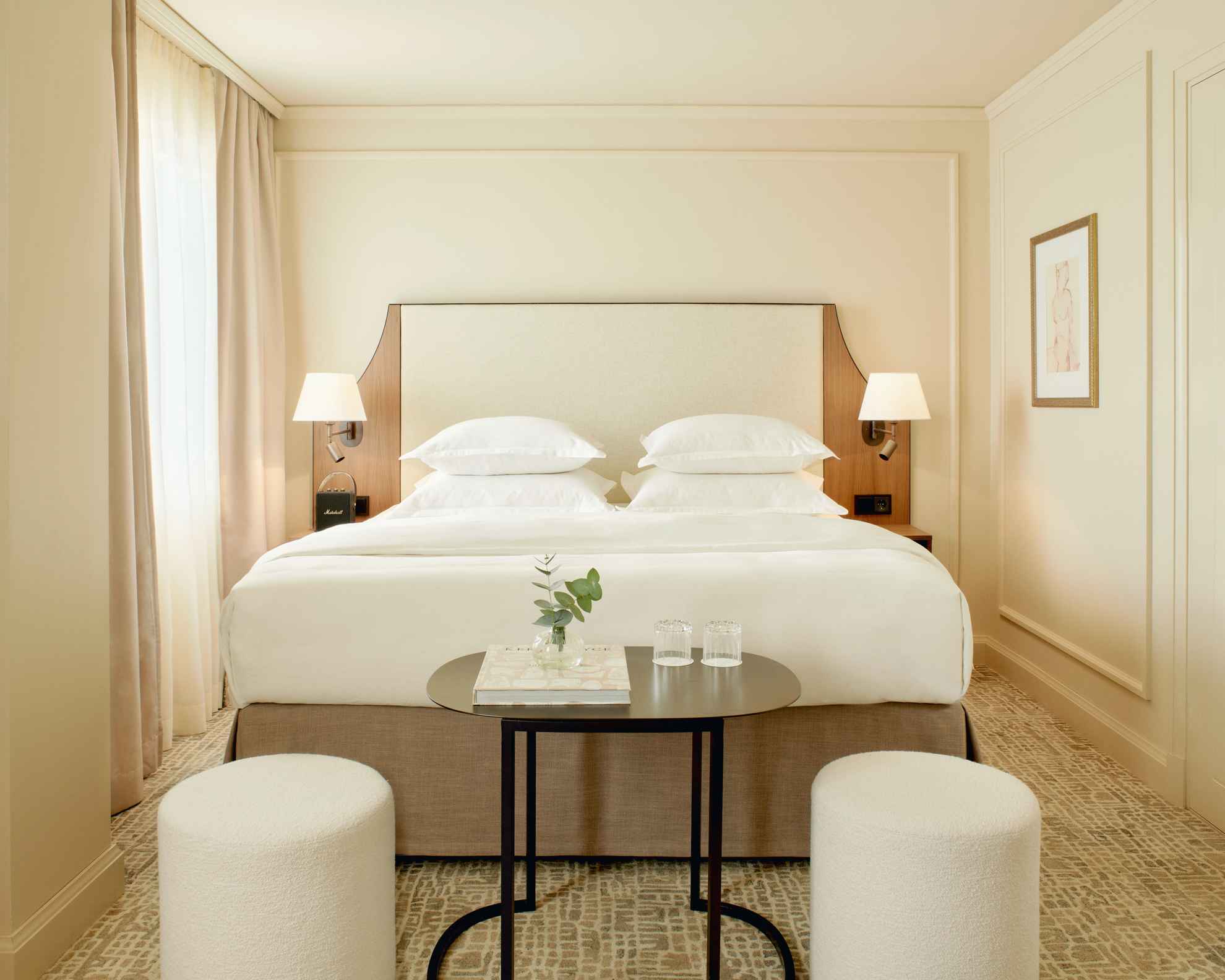 Chambre d'hôtel à la Villa Dahlia. La chambre a des murs clairs, un lit double, une petite table foncée et deux sièges blancs.