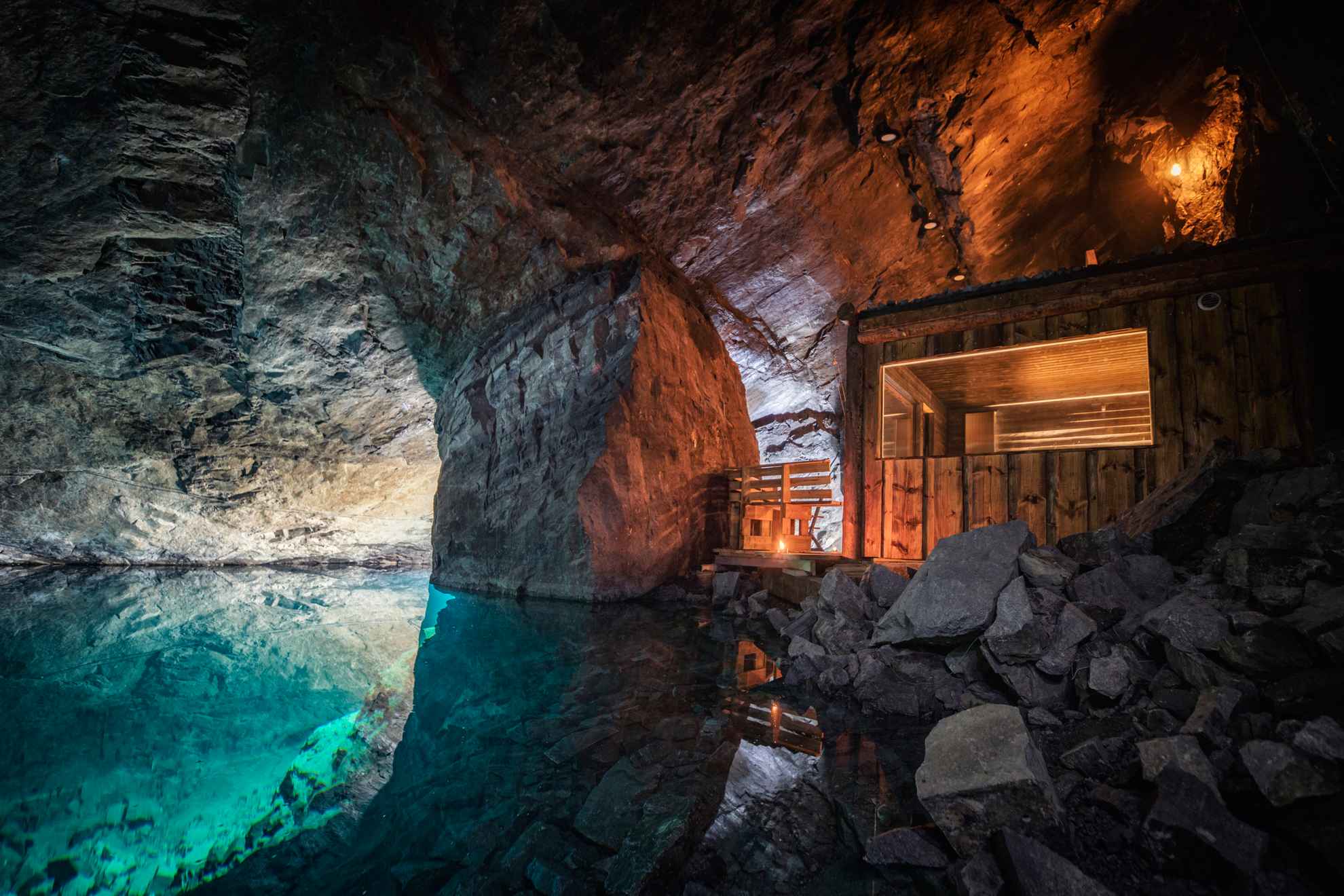 Un sauna en bois au bord d'une eau bleue et claire à l'intérieur d'une mine.