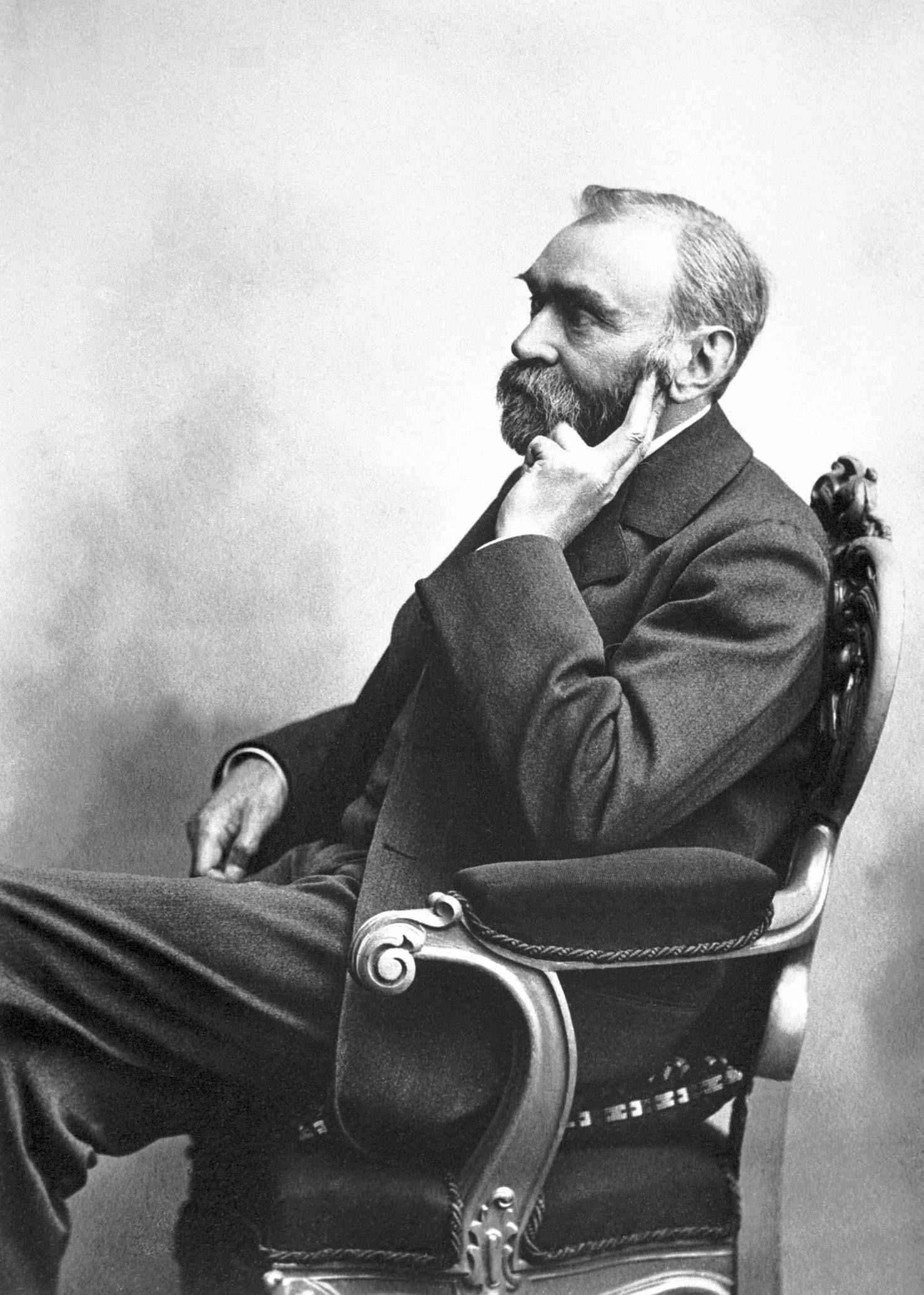 Un vieux portrait en noir et blanc d'Alfred Nobel assis sur une chaise.