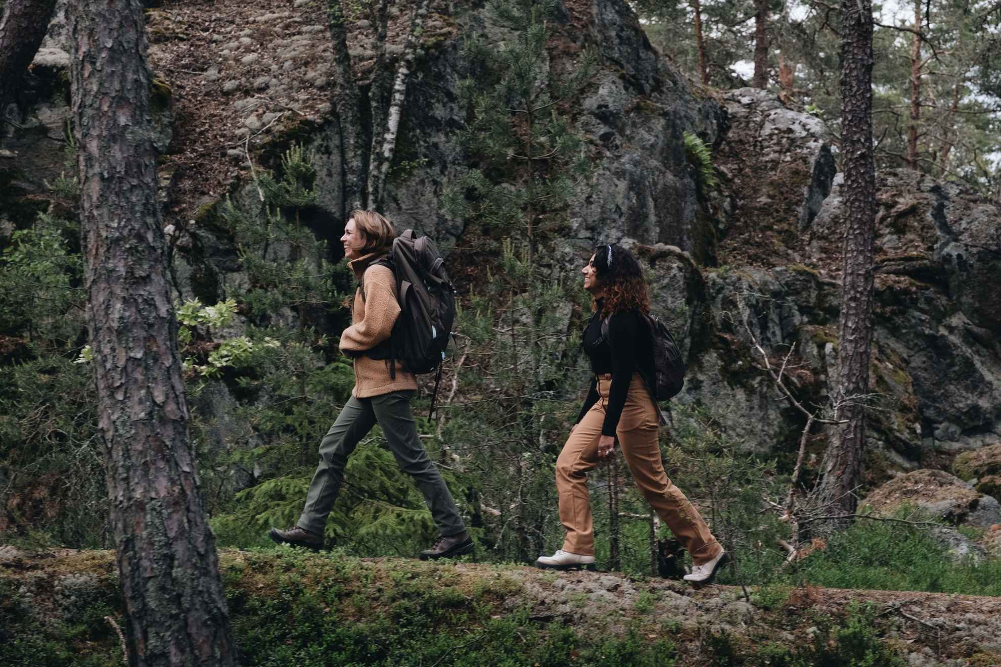 Deux femmes en vêtements de plein air faisant de la randonnée dans une forêt.