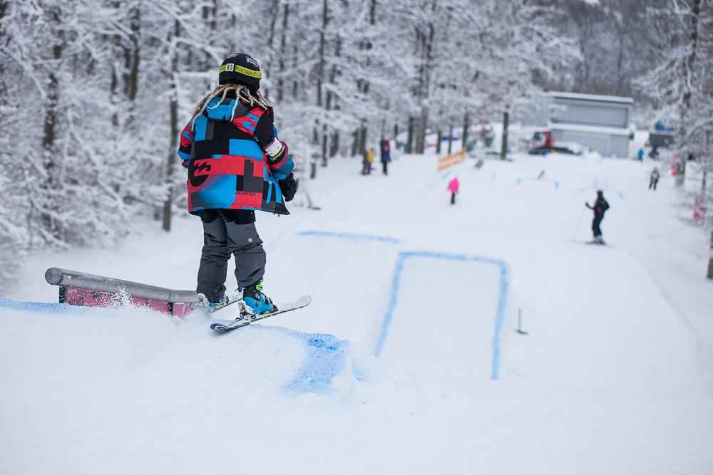 Un enfant skiant sur une piste de ski avec de petits tremplins.