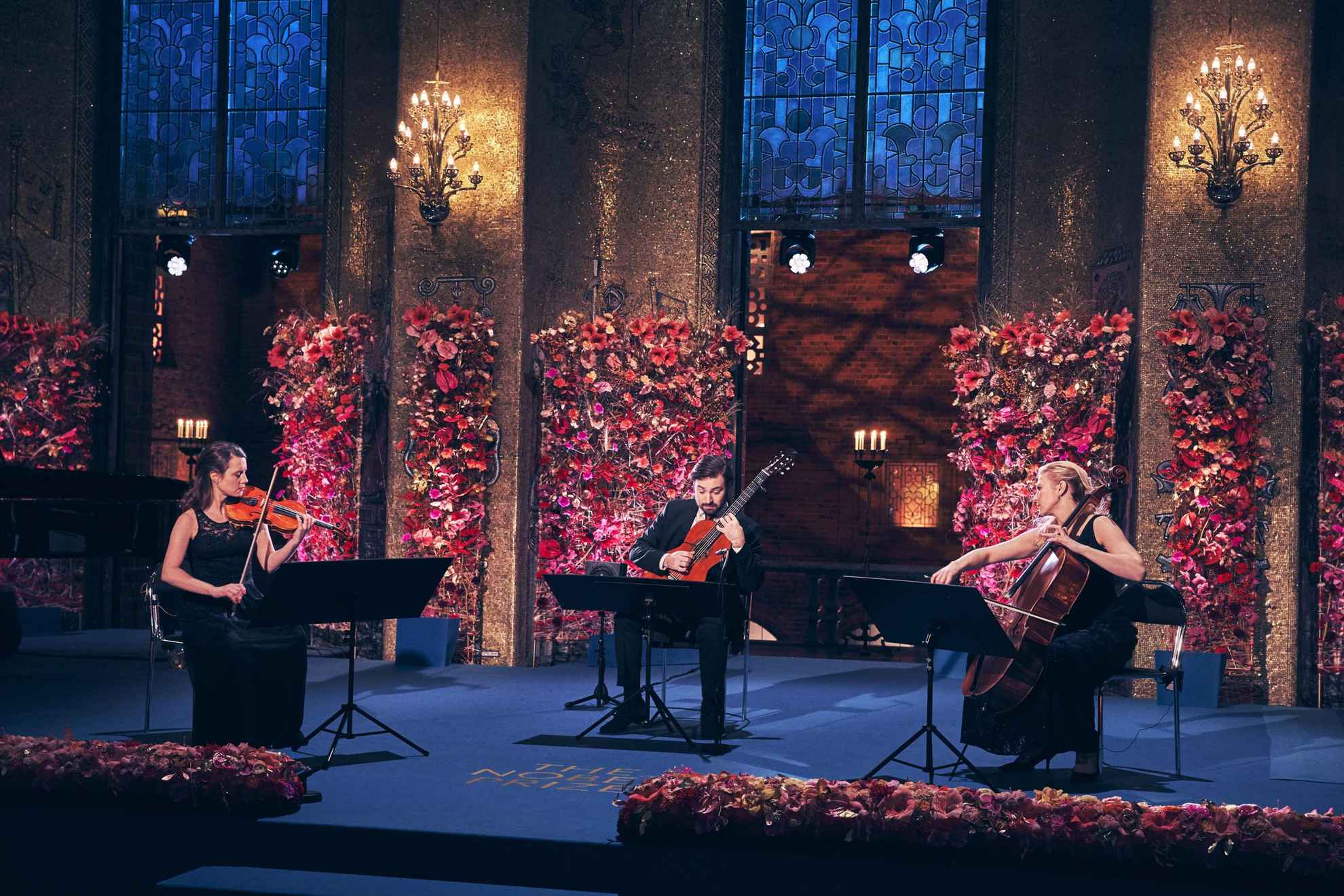 Un guitariste, une violoncelliste et une violoniste se produisant lors de la cérémonie du prix Nobel.