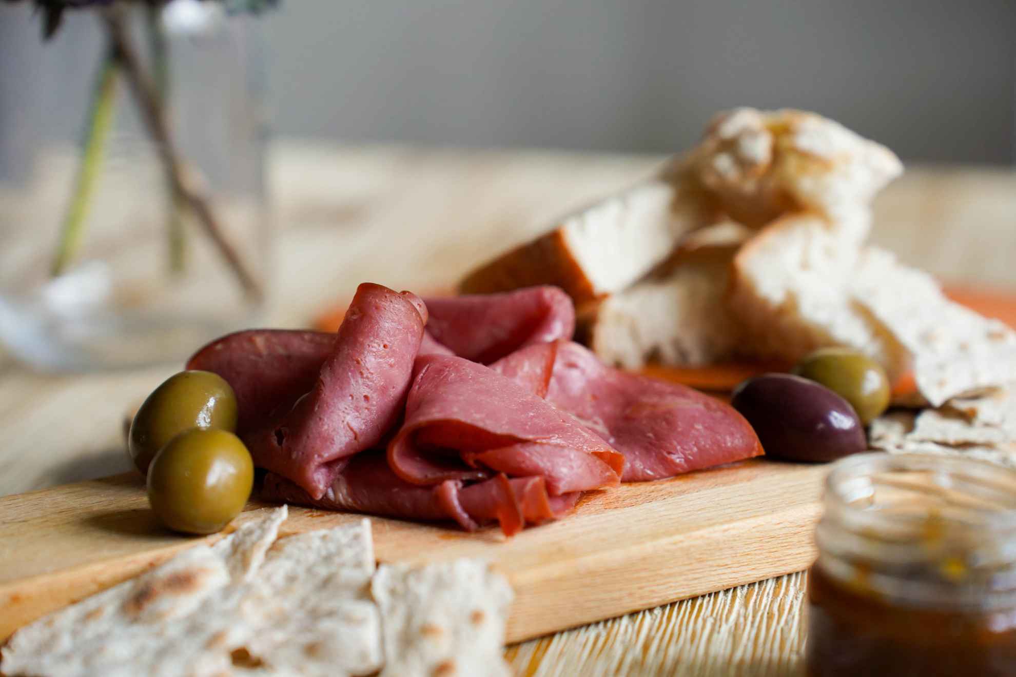 Une planche de charcuterie avec des olives, du pain et de la viande de renne fumée.