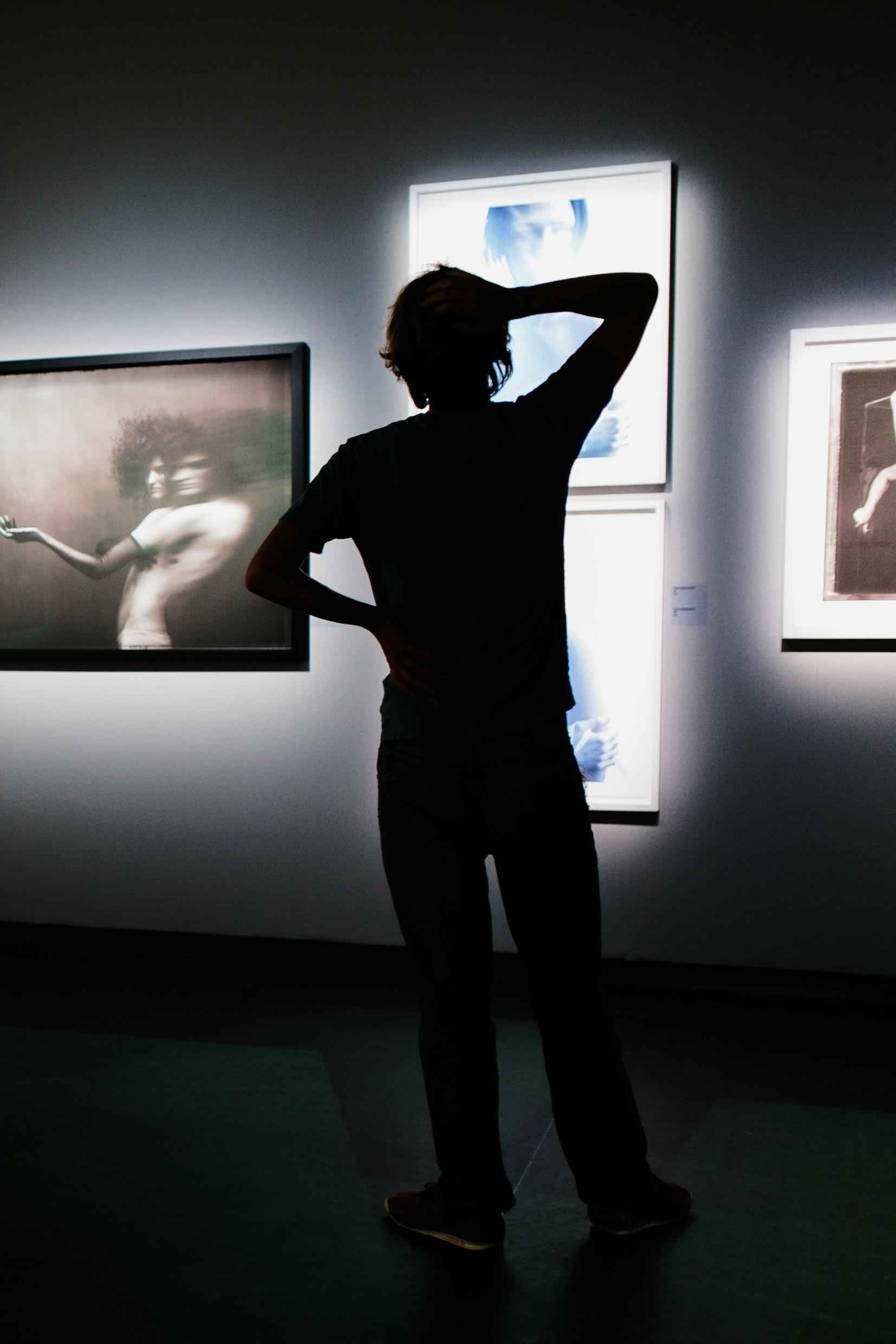 La silouhette d'une personne regardant des photos dans une exposition.