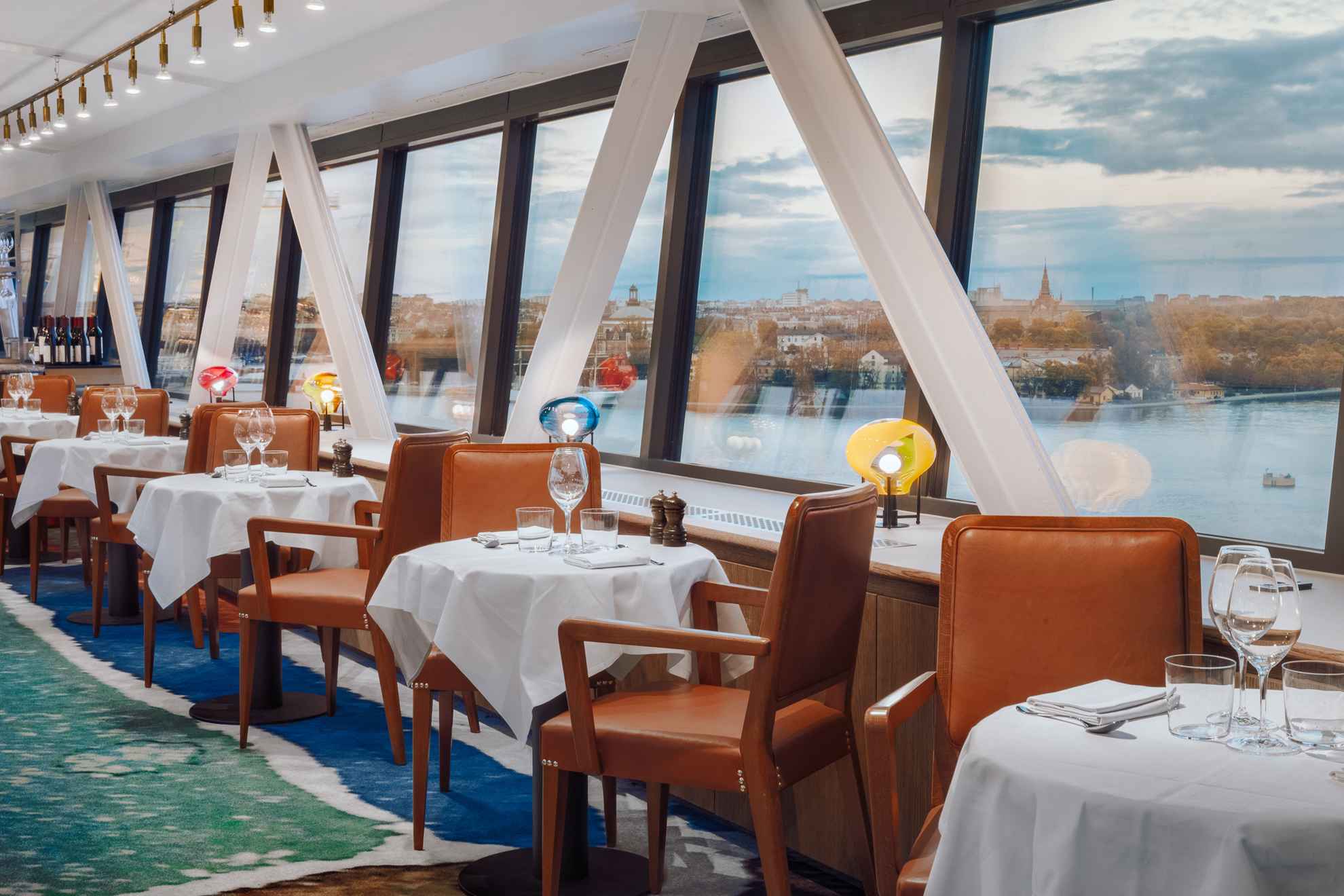 Des tables et des chaises du restaurant Gondolen avec de grandes fenêtres donnant sur l'eau.