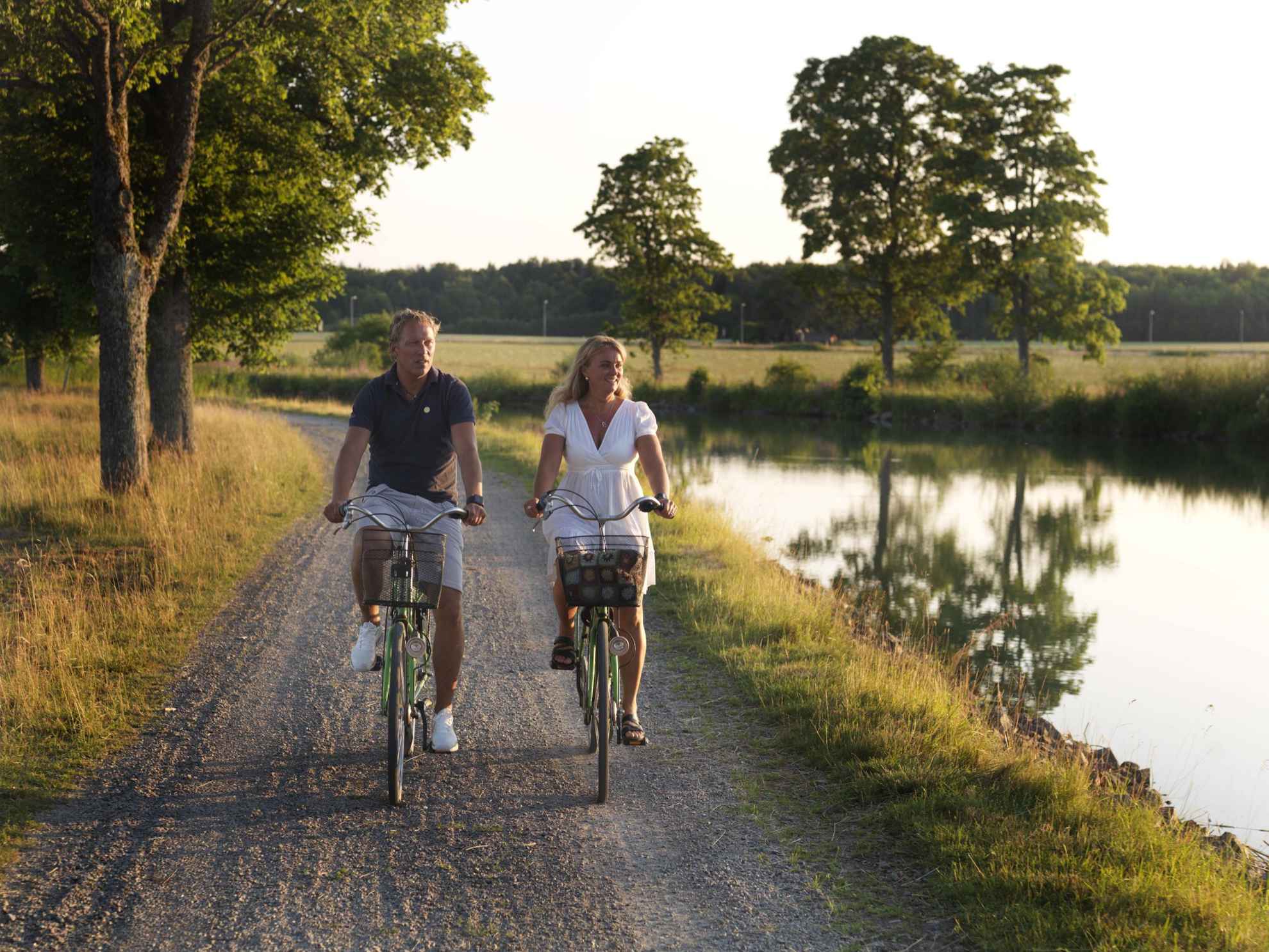 Un homme et une femme en train de faire du vélo le long du canal Göta en été.