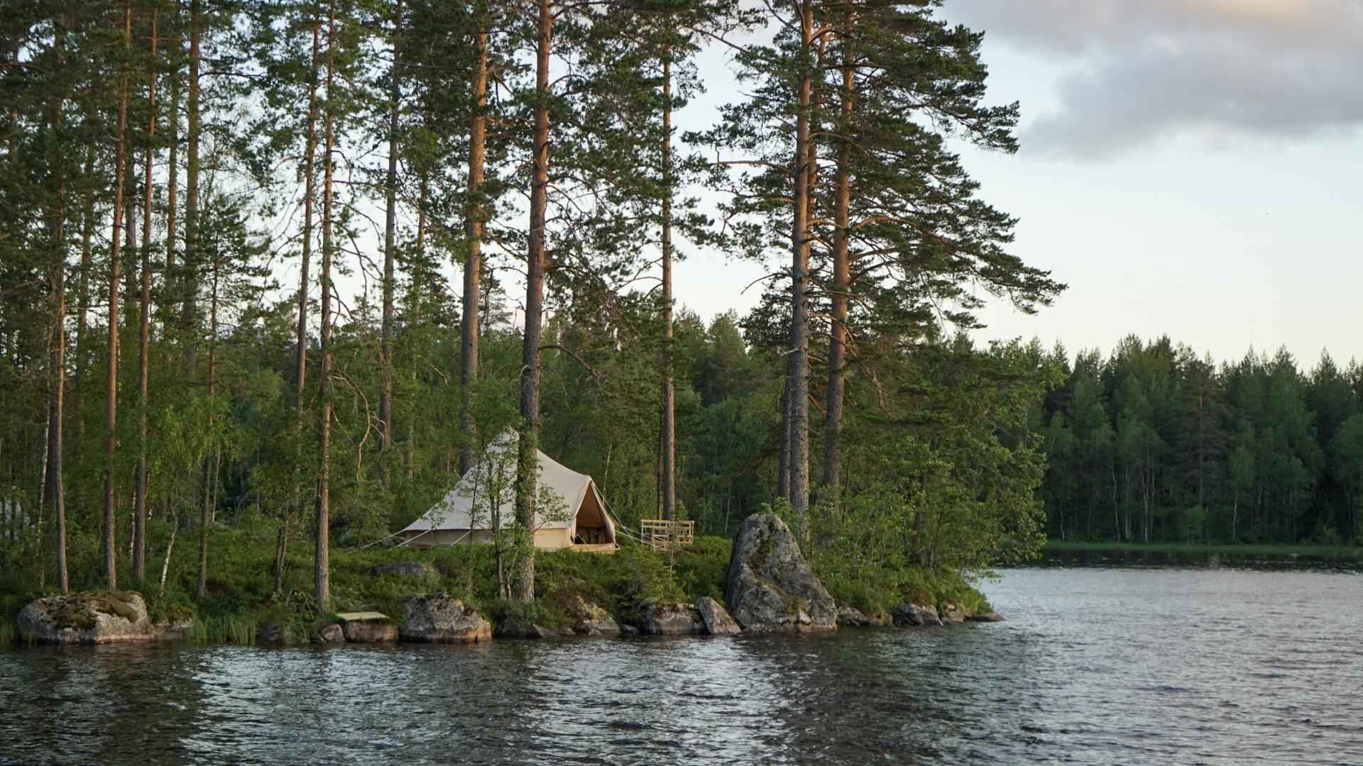 Une luxueuse tente en toile située au bord d'un lac dans une forêt du Värmland.