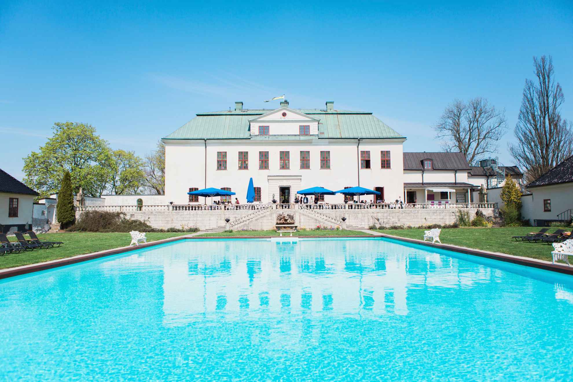 La cour arrière du château de Häringe, avec une piscine et une grande terrasse.