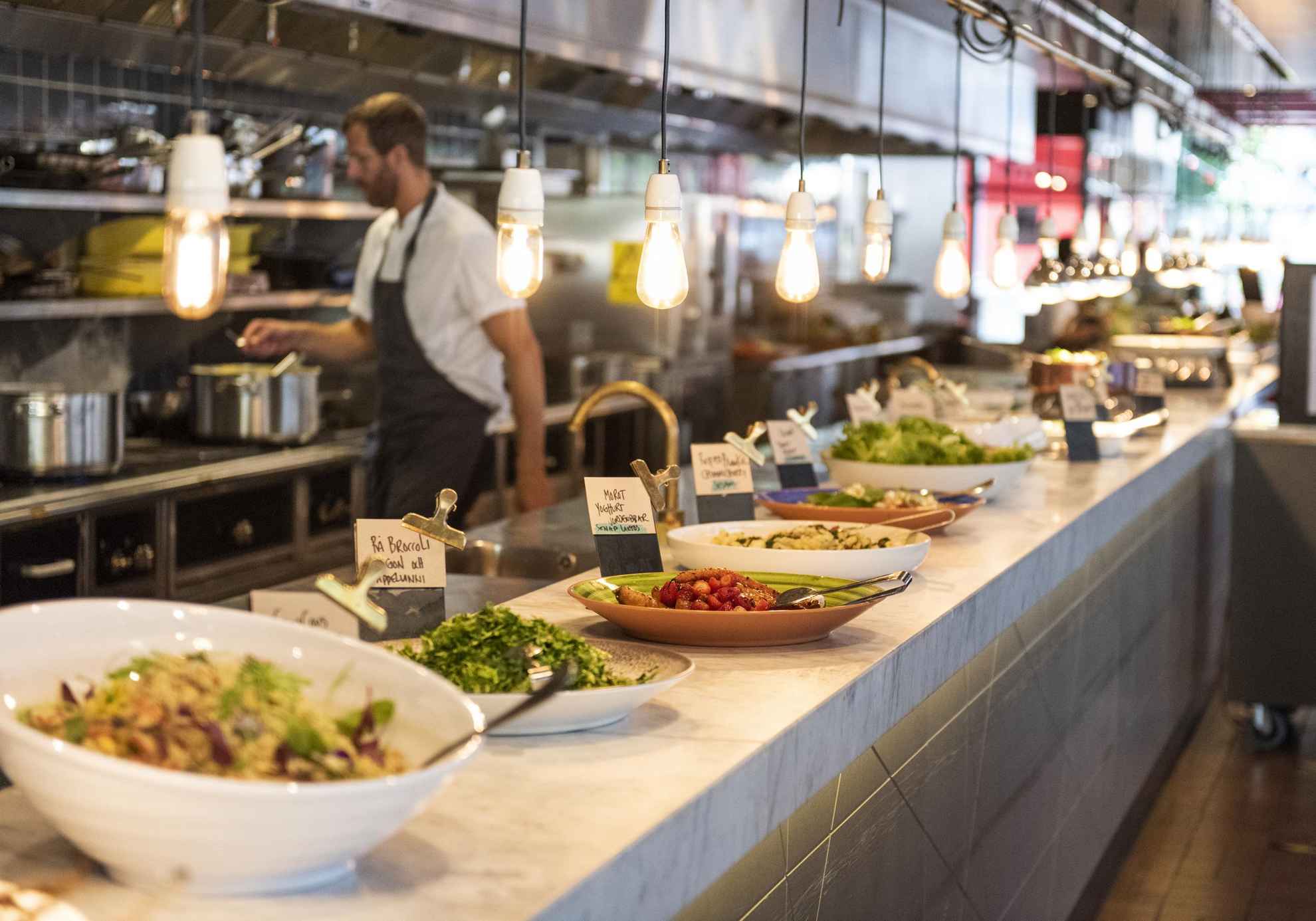 Des assiettes remplies de nourriture sont posées sur un comptoir devant une cuisine ouverte dans un restaurant.