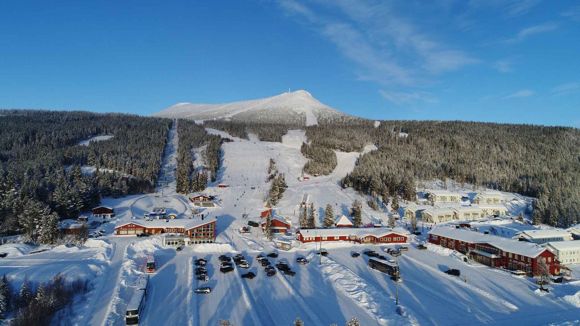 Une station de ski avec des maisons rouges et des pistes enneigées.