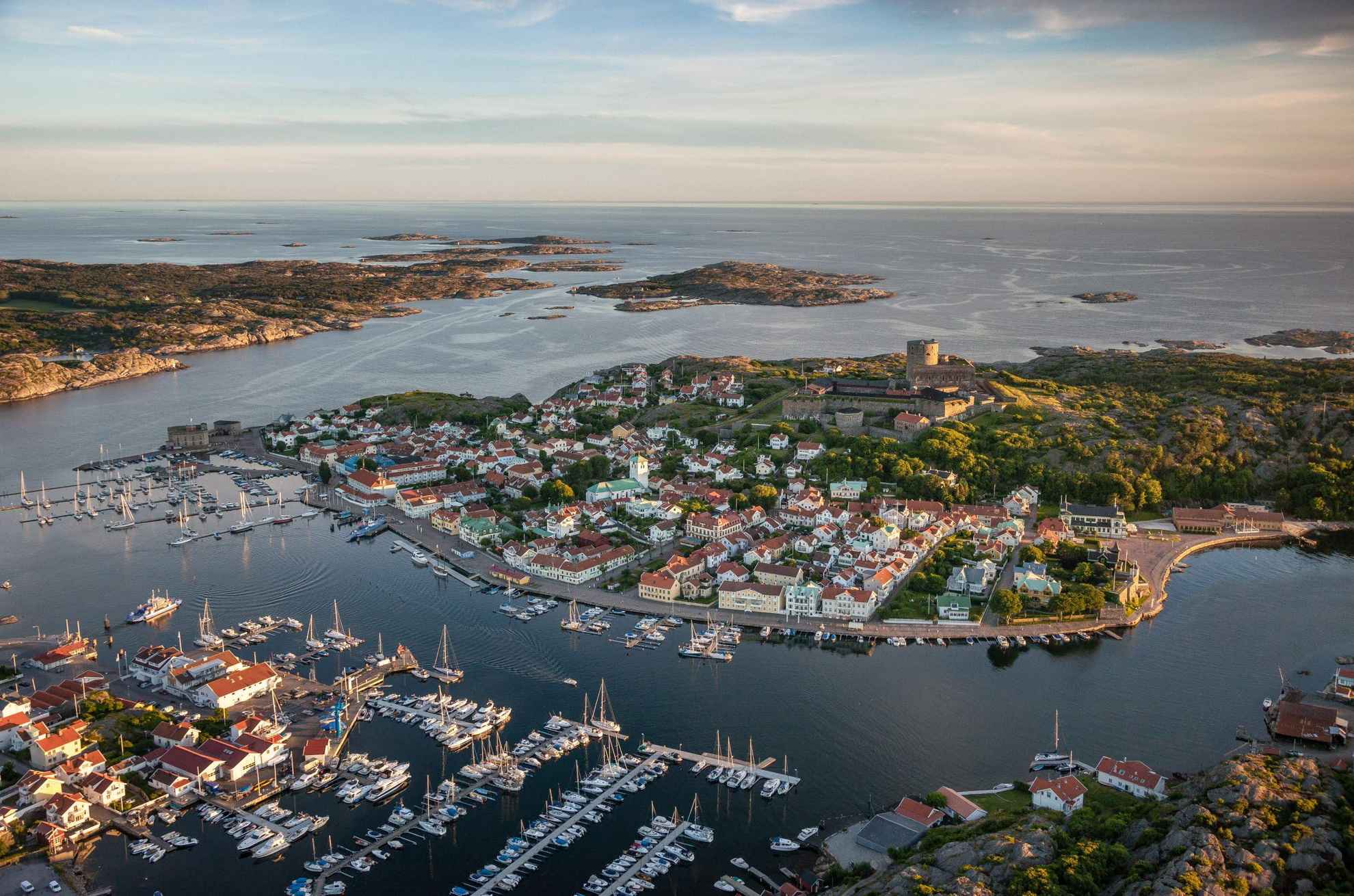 Vue aérienne de la petite ville de Marstrand avec de nombreux voiliers en premier plan. La forteresse de l'île se situe au centre et on voit l'archipel en arrière-plan.