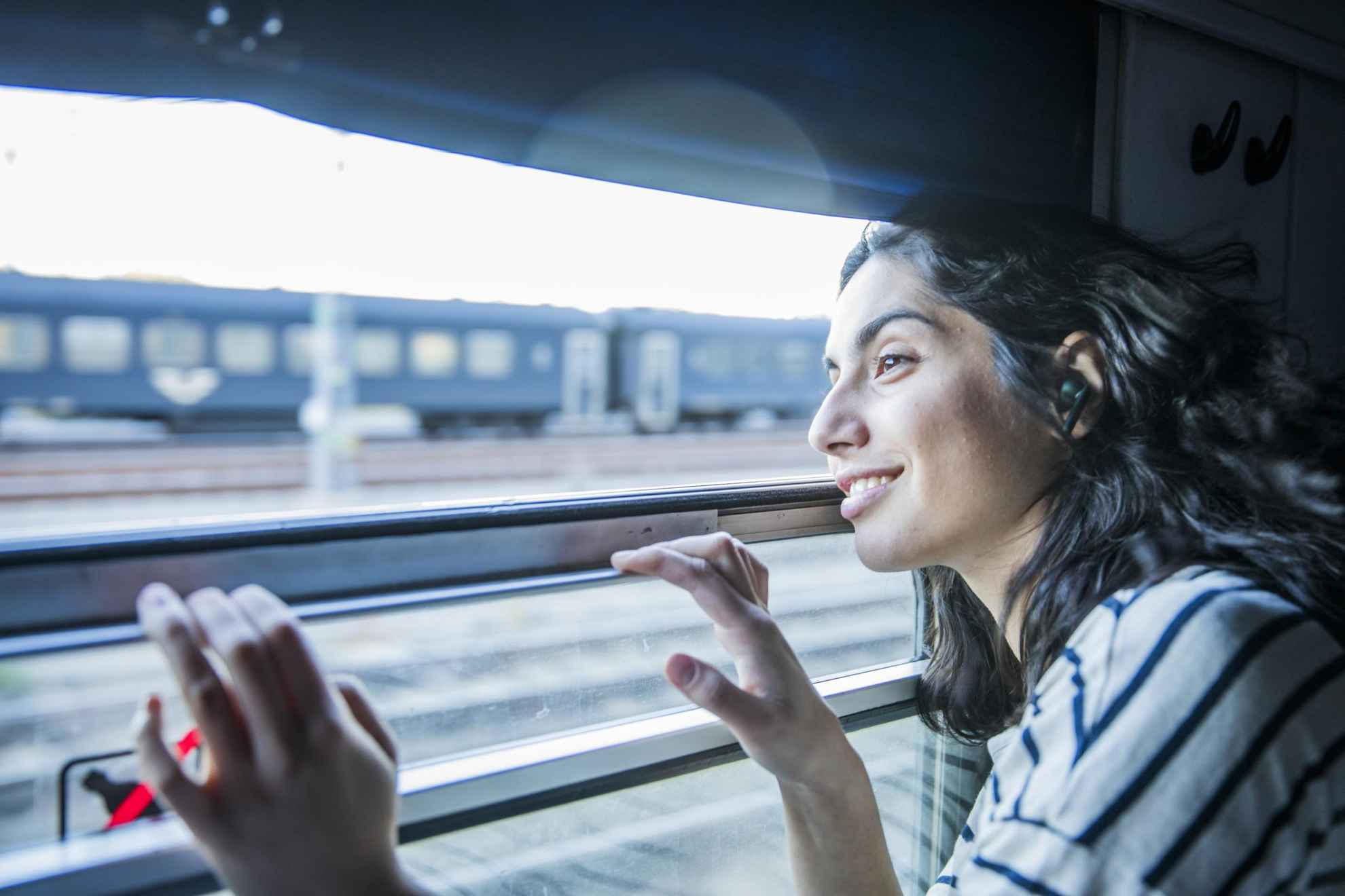 Une femme regarde par la fenêtre d'un train qui en croise un autre.