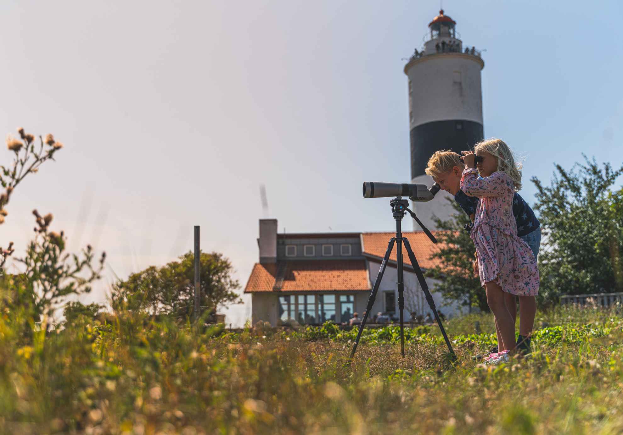 Une fille et un garçon observent des oiseaux à l'aide d'un télescope près du phare Långe Jan sur l'île d'Öland.