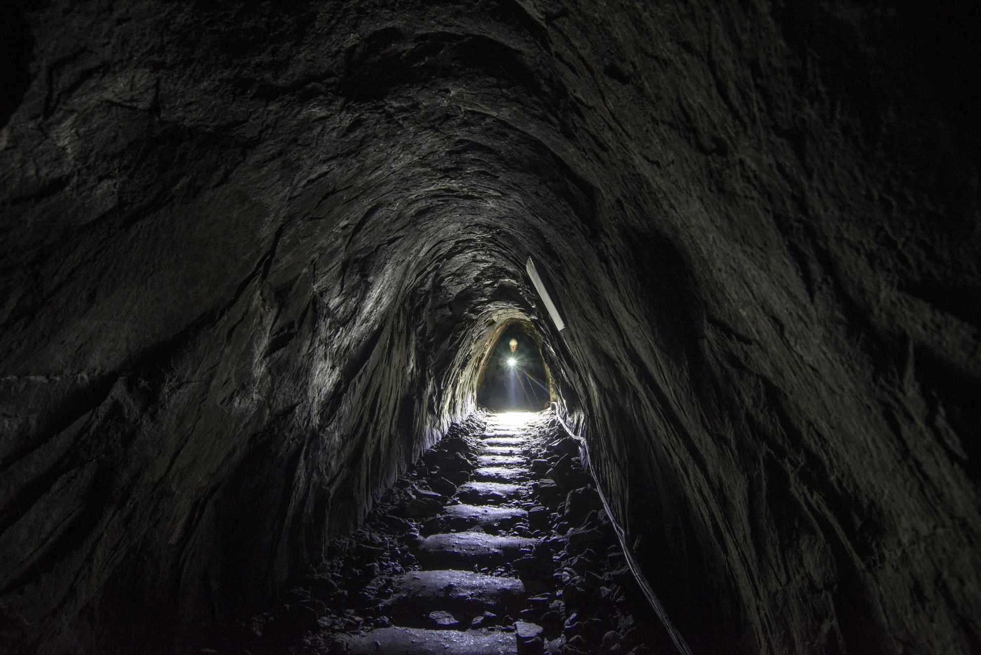 Une personne munie d'une lampe de poche marche dans un passage souterrain de la mine d'argent de Sala.