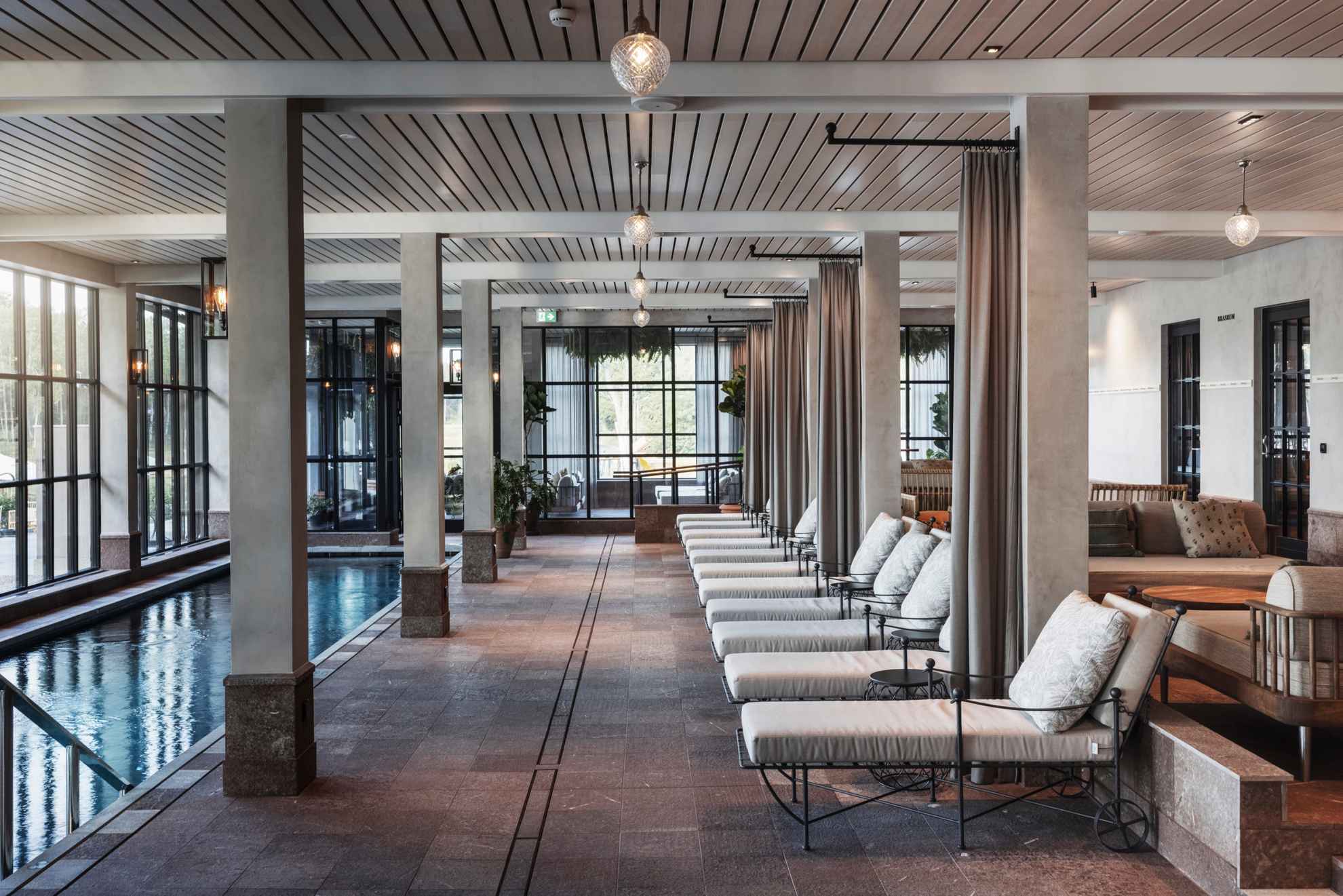 Chaises longues, canapés et tables à côté d'une piscine intérieure dans le spa de Smådalarö Gård.