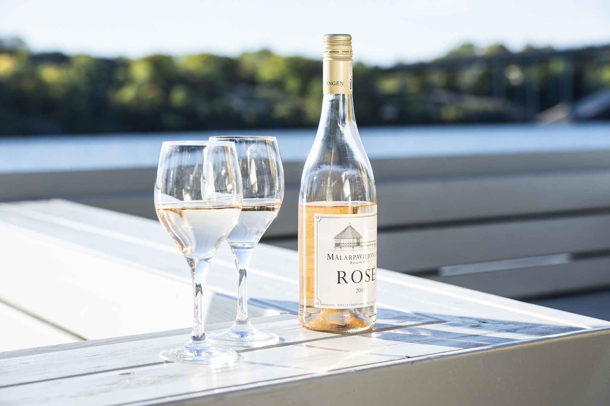 Deux verres de vin et une bouteille de rosé sur une table à côté de la mer