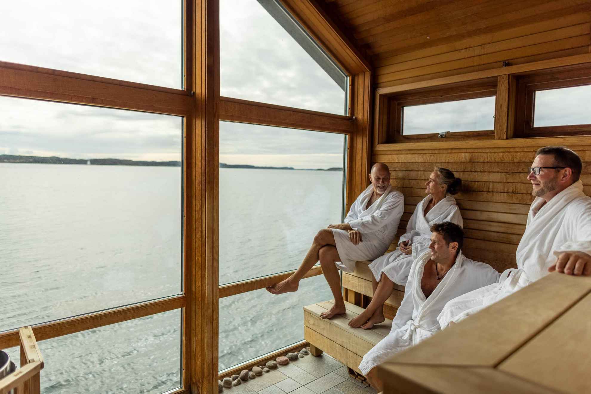 Quatre personnes profite du sauna et de la vue sur la mer.