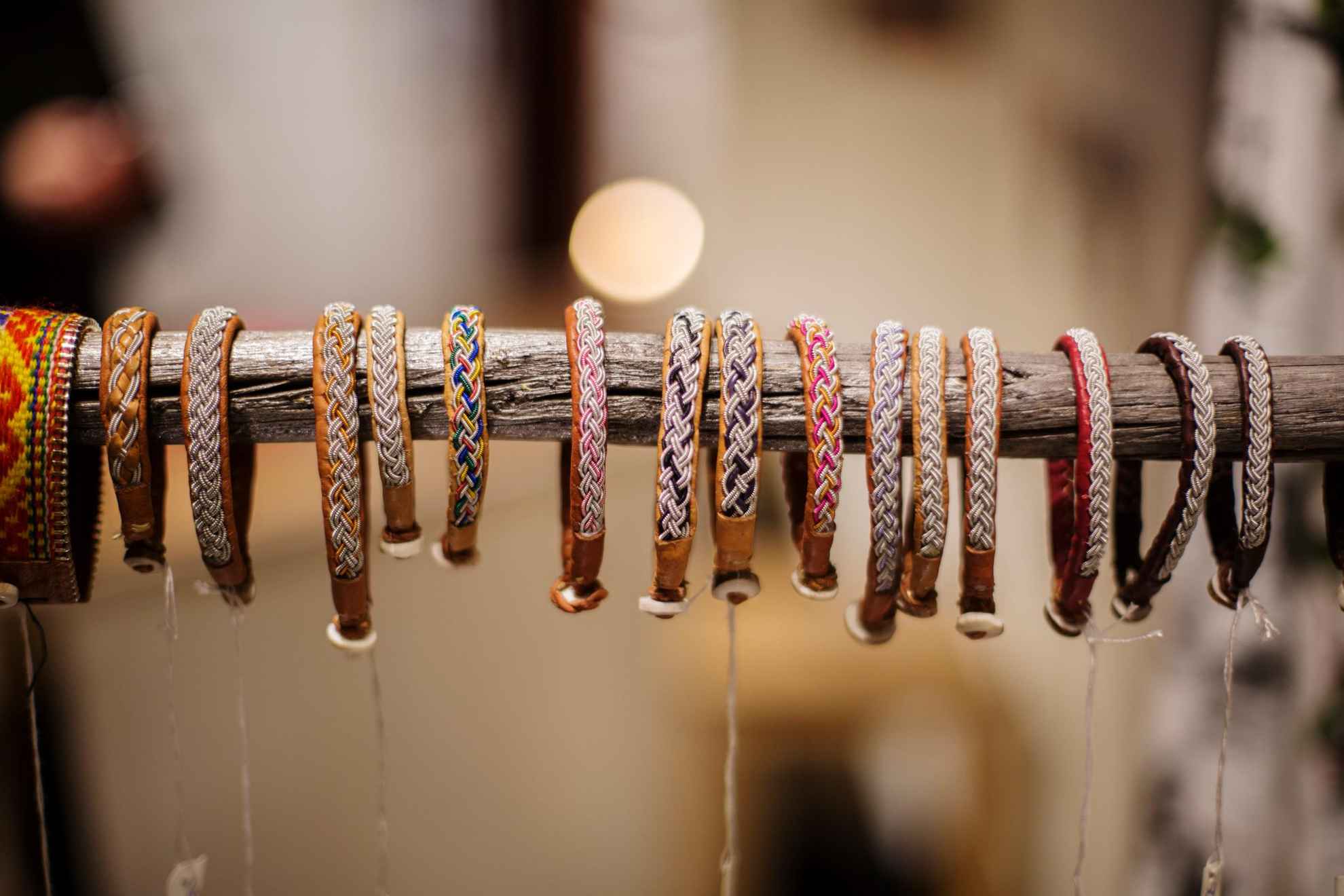 De nombreux bracelets en cuir de renne et fil d'étain, suspendus à un long bâton.