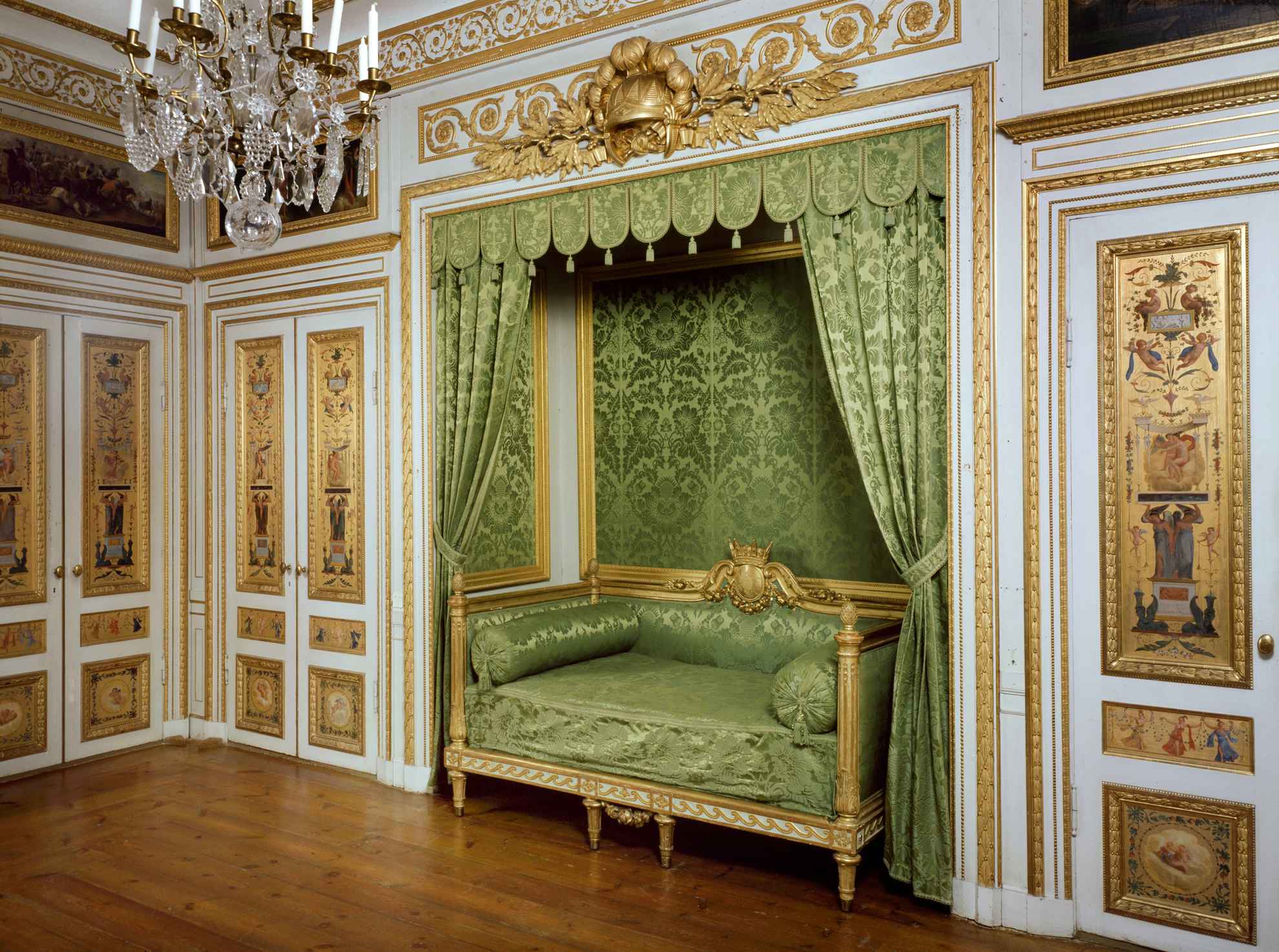 Une chambre à coucher au palais de Tullgarn, décorée d'un canapé vert, de murs dorés et d'un lustre.