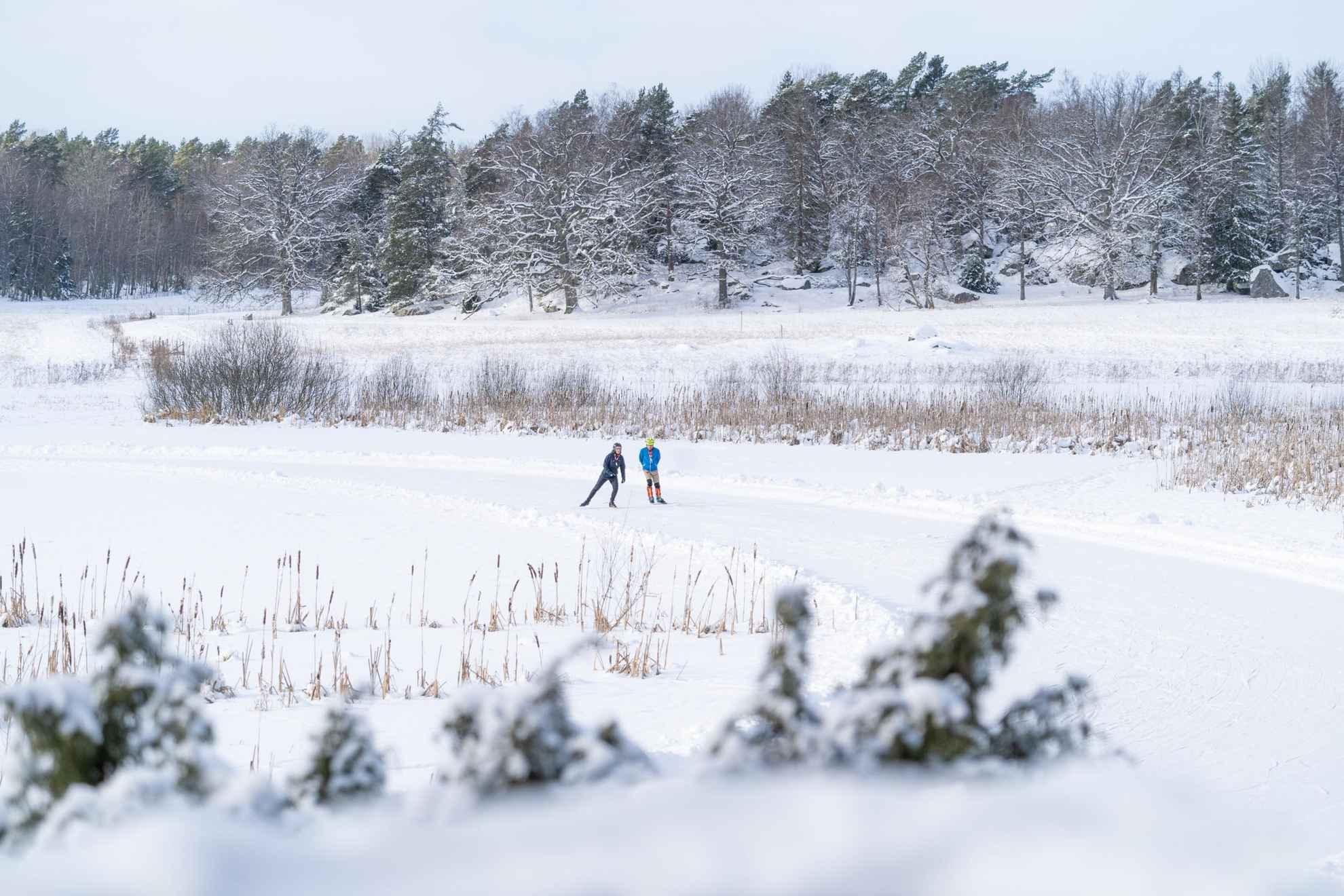 Un paysage couvert de neige avec deux personnes en train de faire du patin à glace.