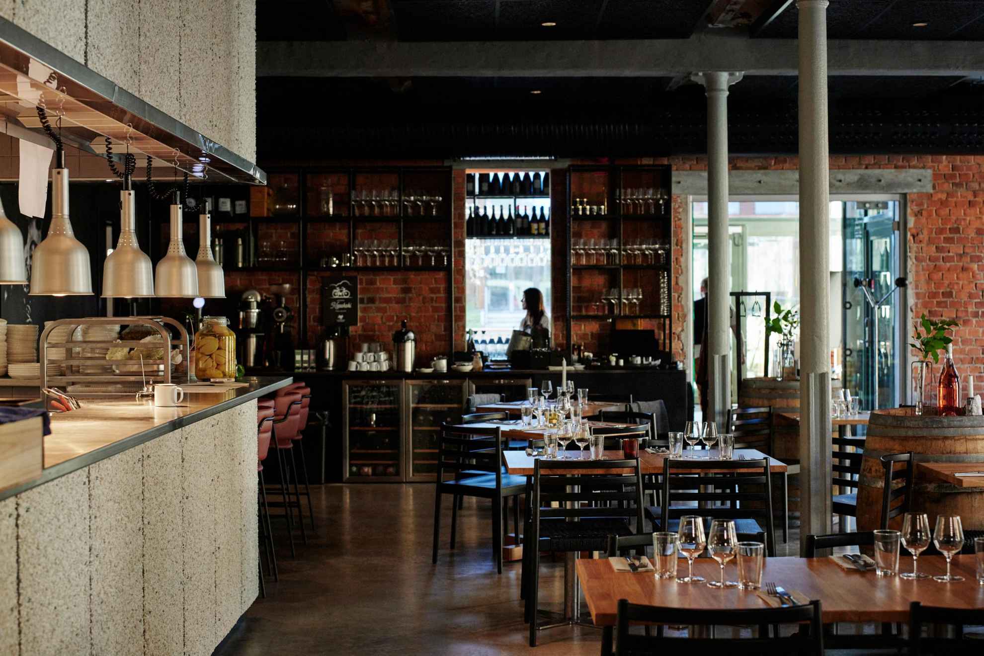 On voit l'intérieur d'un restaurant à vin avec plusieurs tables et sur la gauche de la photo, le bar du restaurant.