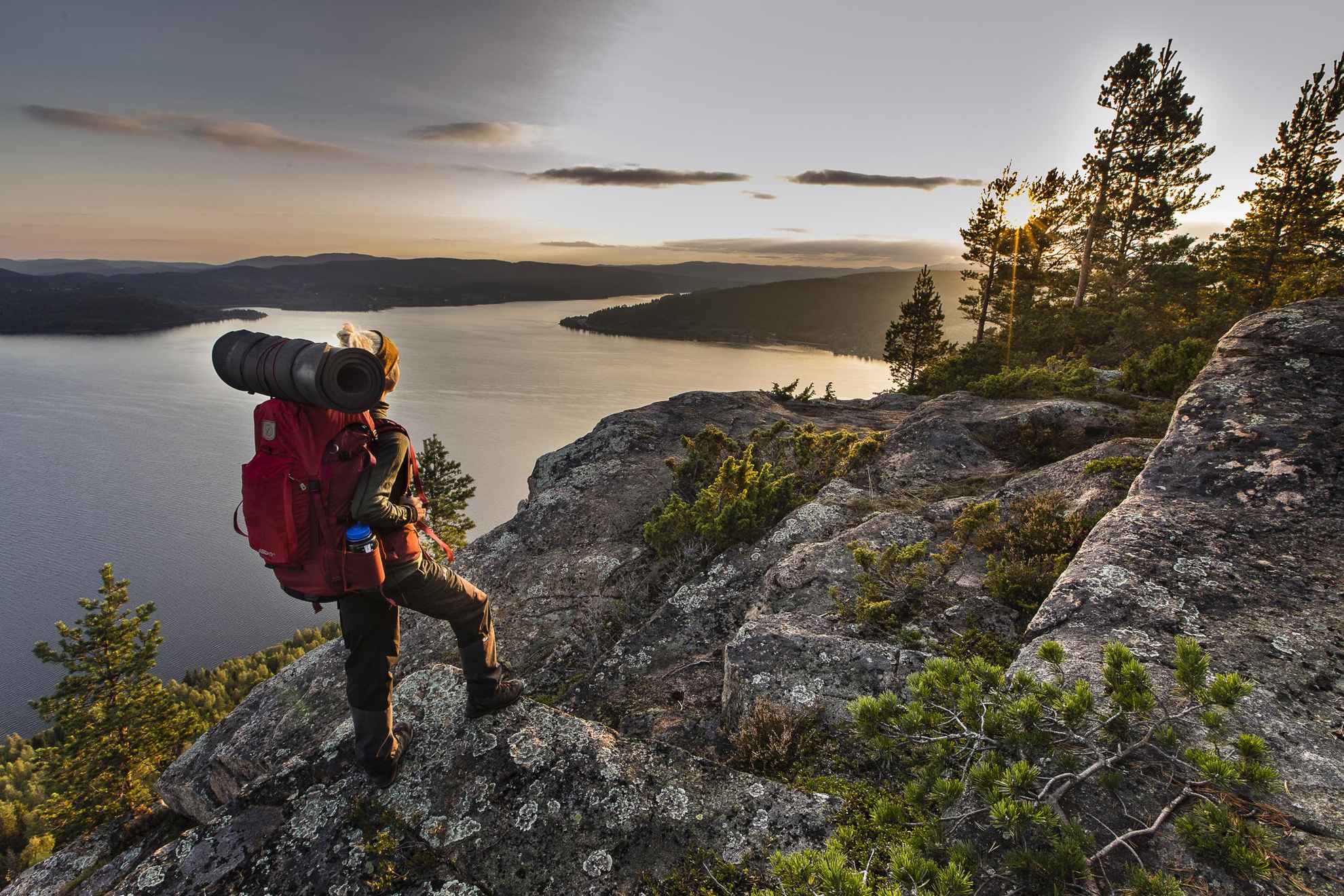 Un randonneur avec un sac à dos admire la vue sur la Haute Côte suédoise.