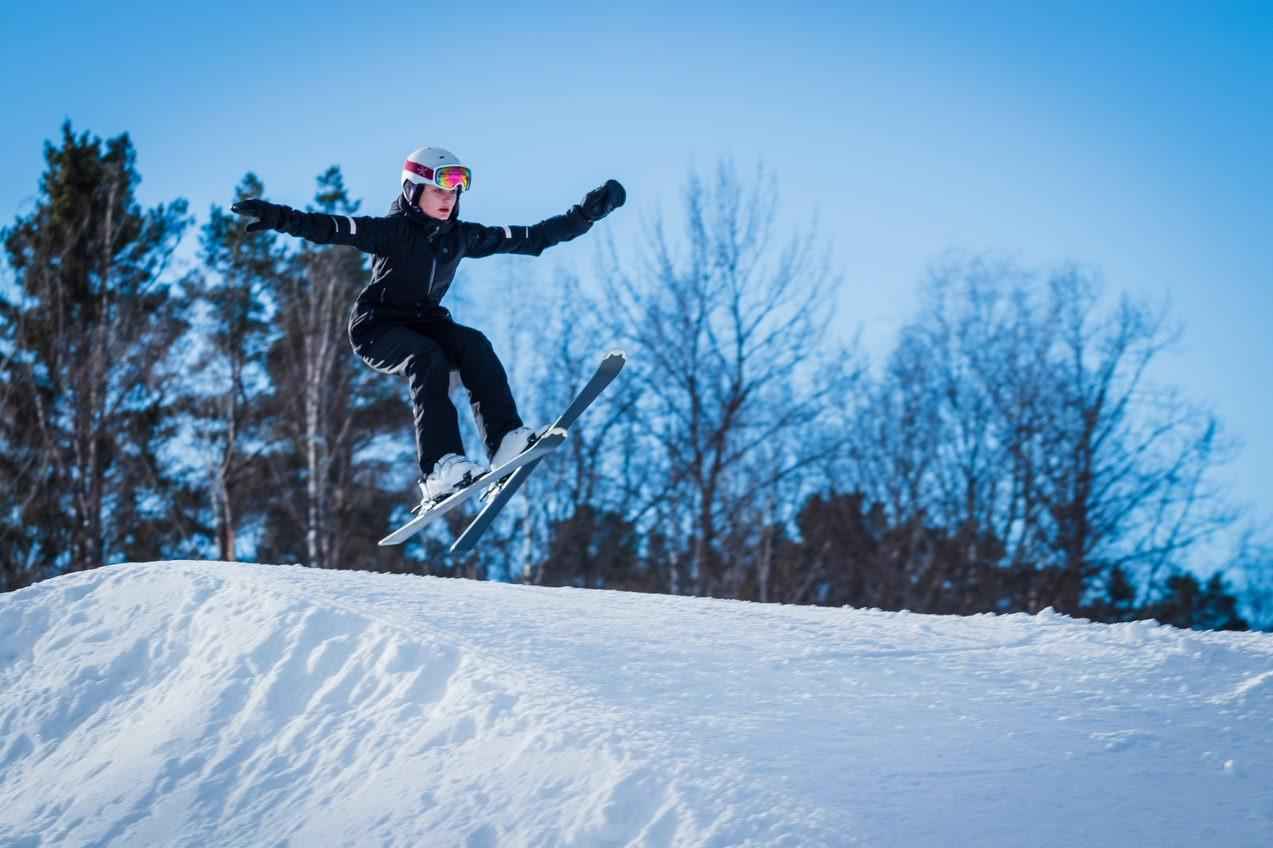 Un enfant sautant avec ses skis sur une piste de ski.