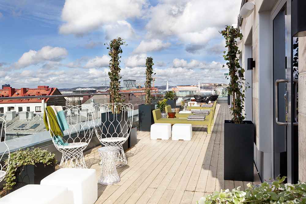 A rooftop with wooden floor and white and yellow furniture.