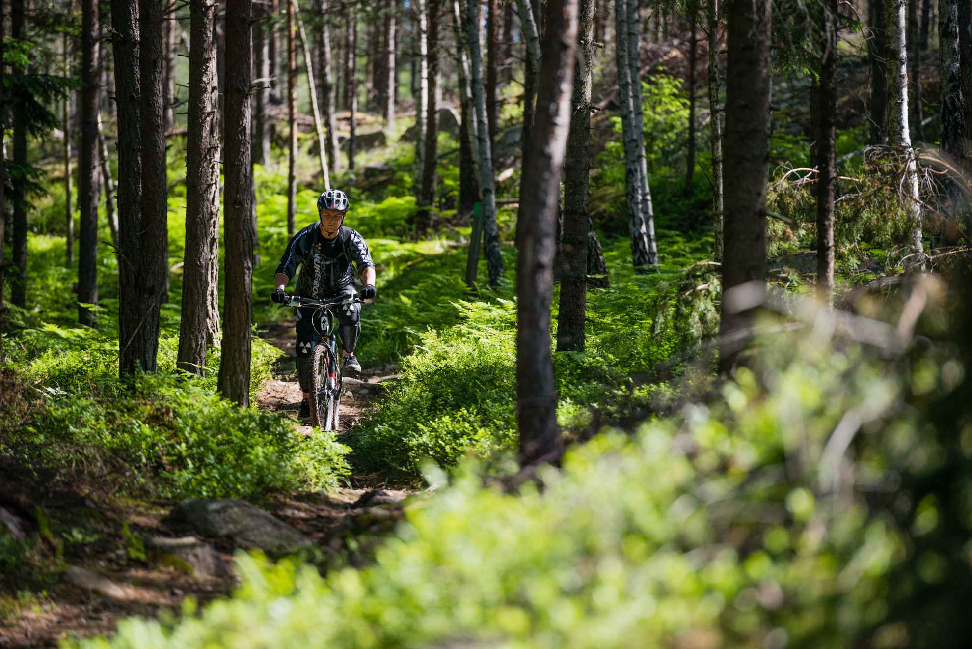 Un homme portant un casque fait du vélo tout terrain dans une forêt luxuriante.
