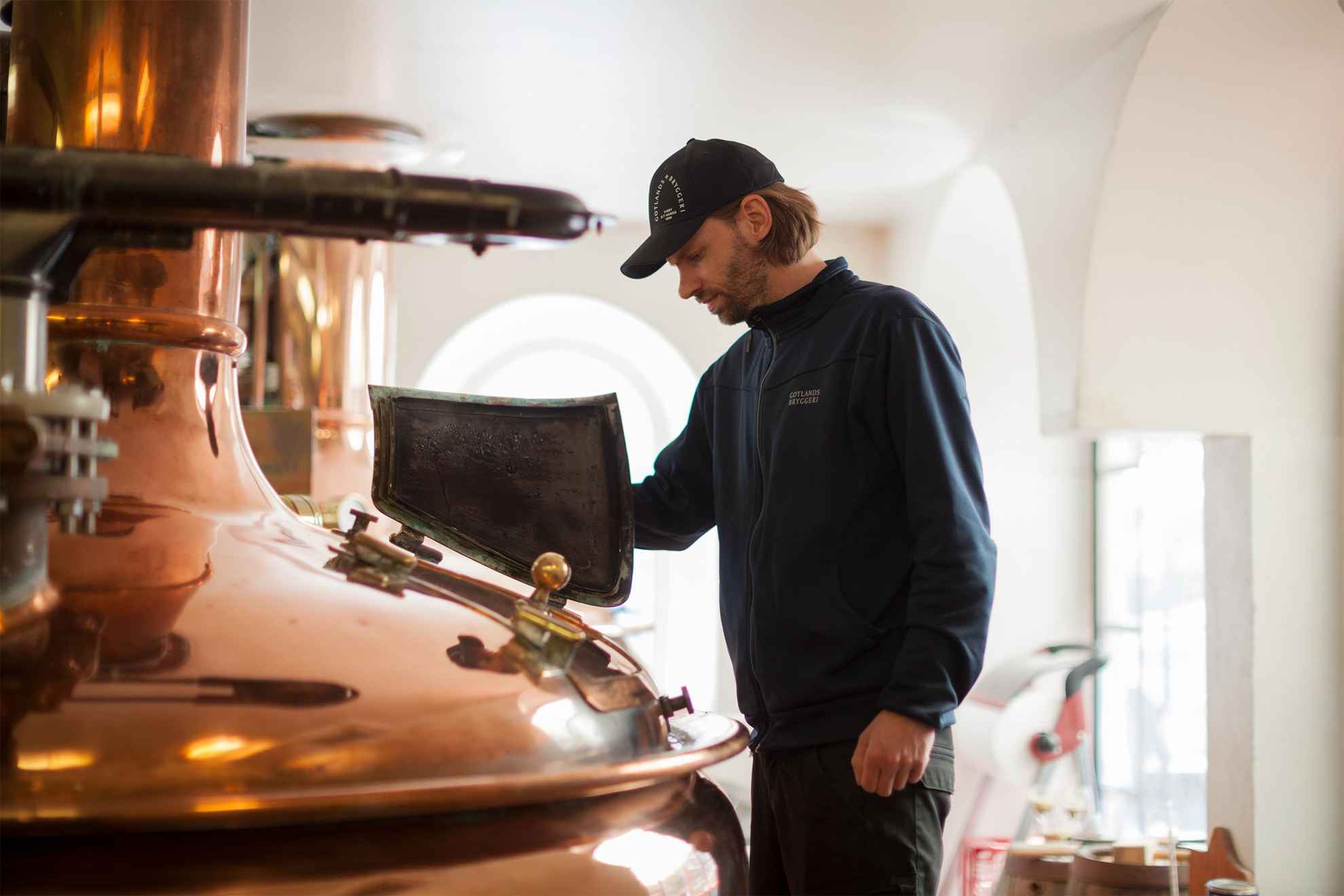 Un employé de Gotlands Bryggeri regarde dans une chaudière en cuivre dans la brasserie.