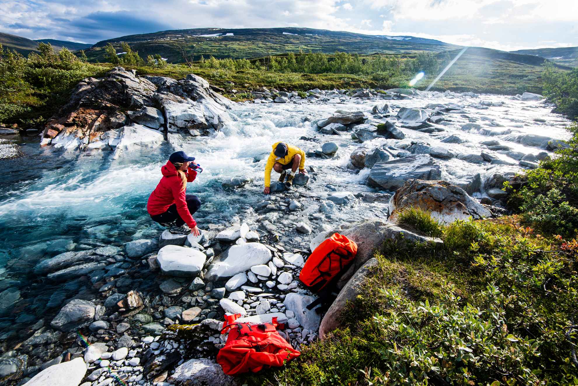 Deux personnes sont en train de boire l'eau de la rivière en Laponie suédoise