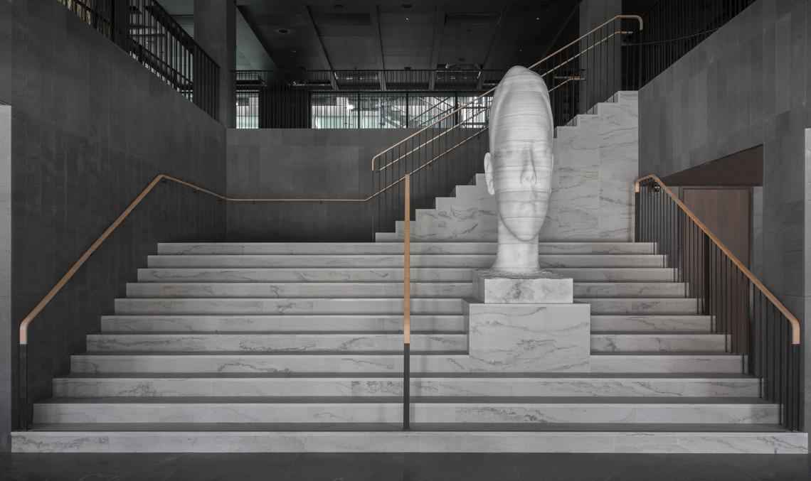 Une sculpture en marbre d'une tête d'homme se trouve sur un escalier en marbre.