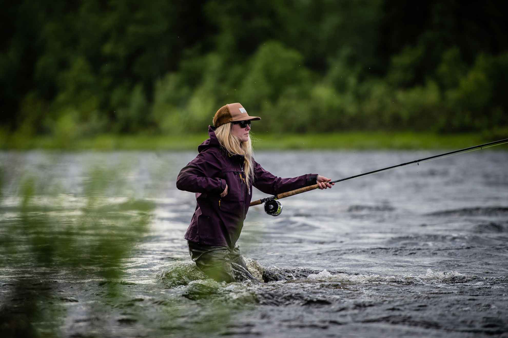 Une jeune fille pêche à la mouche dans une rivière.