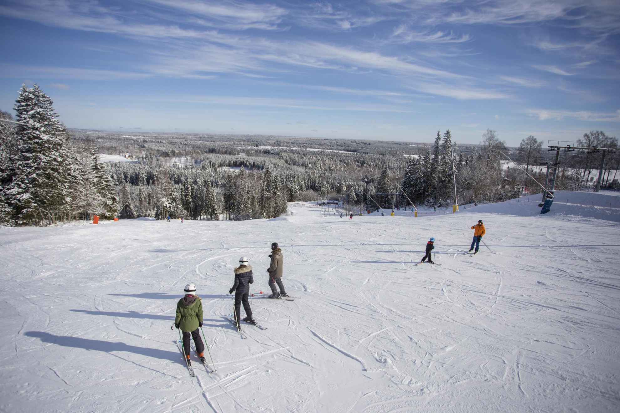 Personnes dévalant une pente en ski avec une vue sur un paysage enneigé.