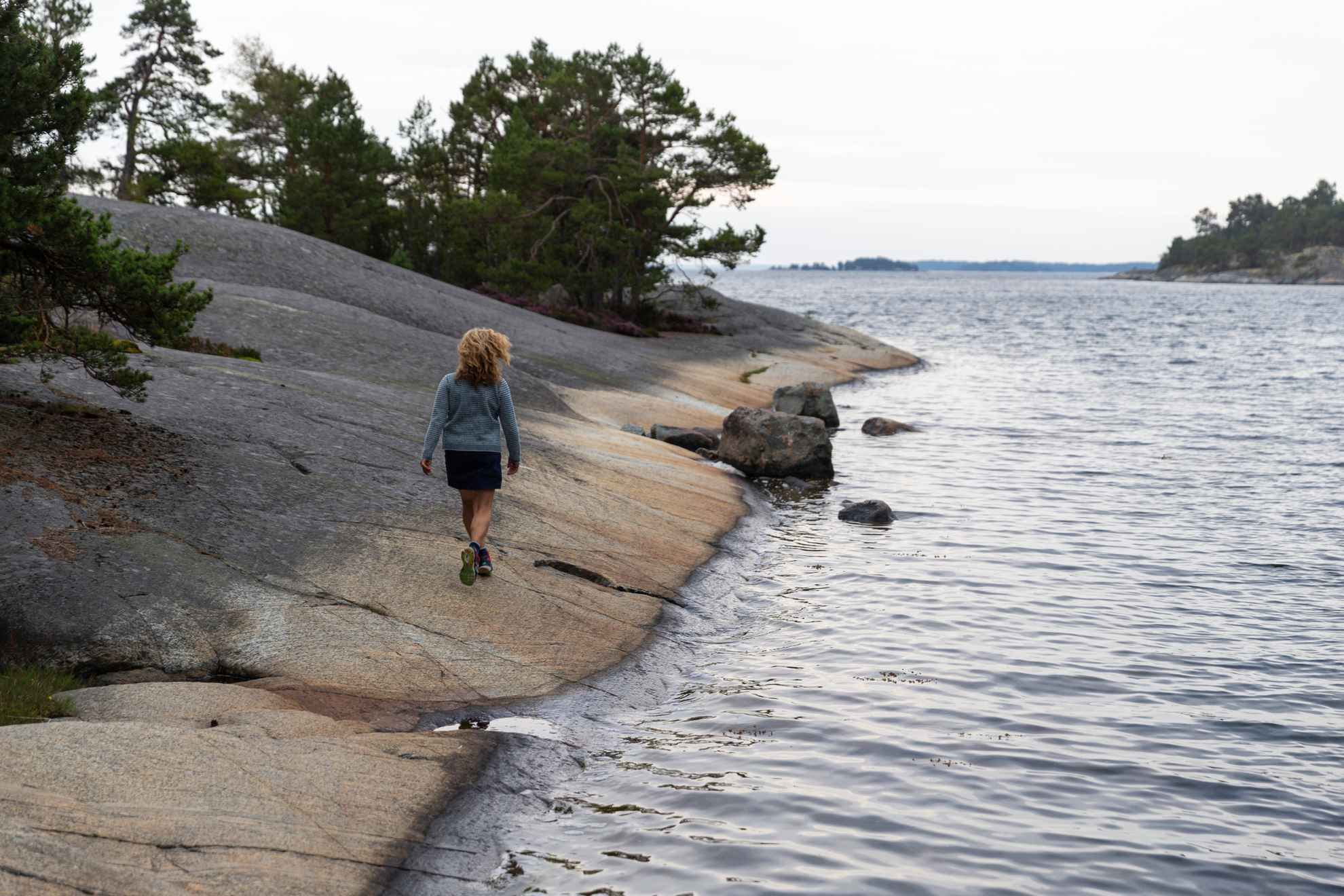 Une femme marche sur les falaises au bord de la mer dans l'archipel de Stockholm.