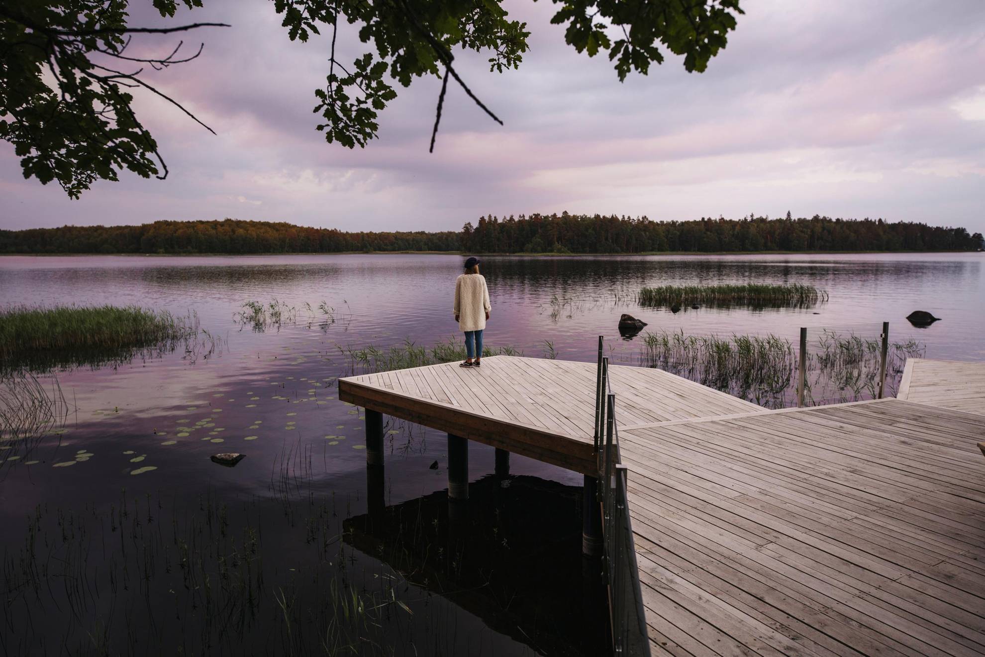 Une femme se tient debout au bord d’un ponton tout en admirant la vue sur le lac.