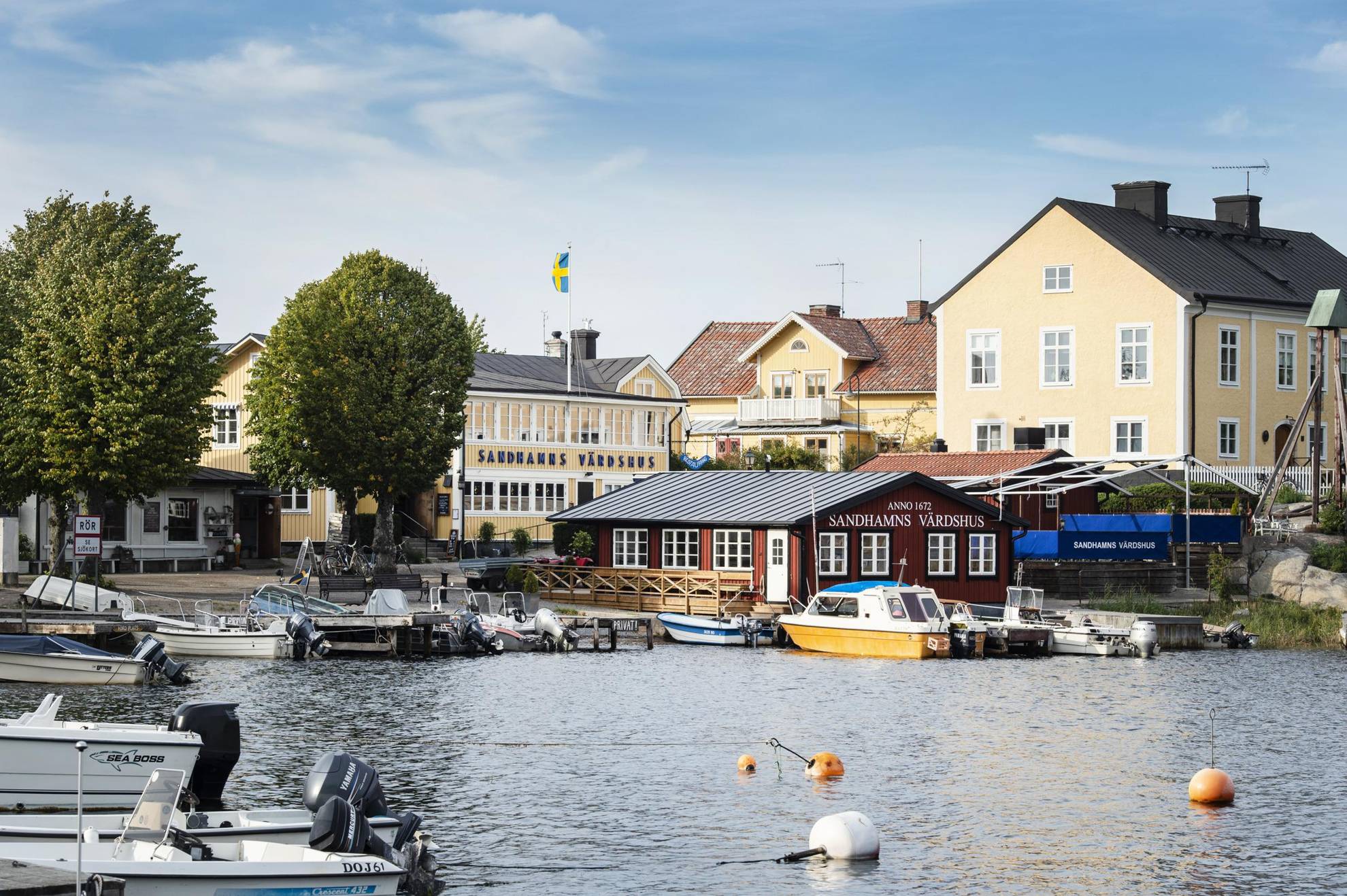 Maisons en jaune et rouge, situées près d'un port avec de nombreux petits bateaux à Sandhamn.