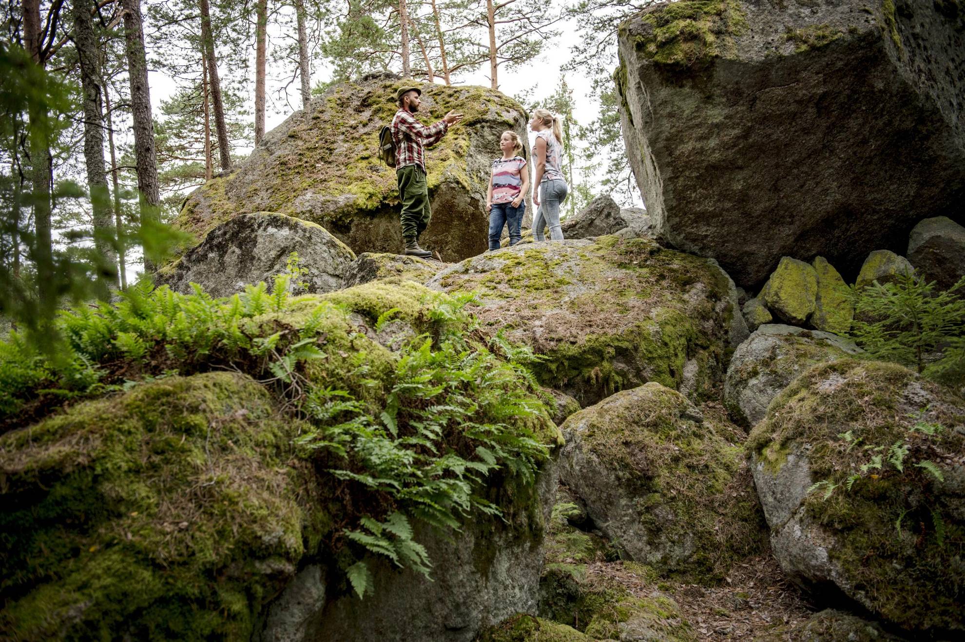 Deux femmes se tiennent debout dans la forêt et écoutent un guide.