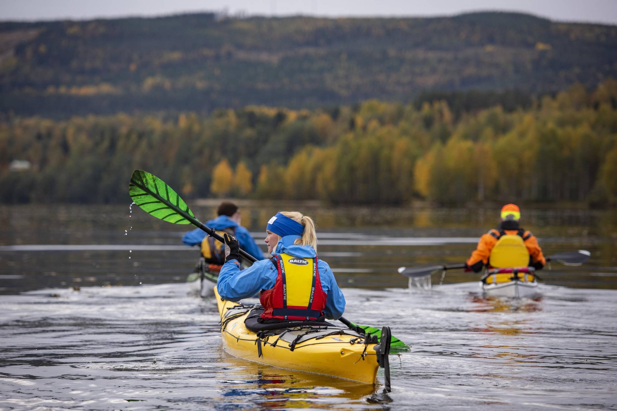 Une femme et deux hommes sont en train de faire du kayak.