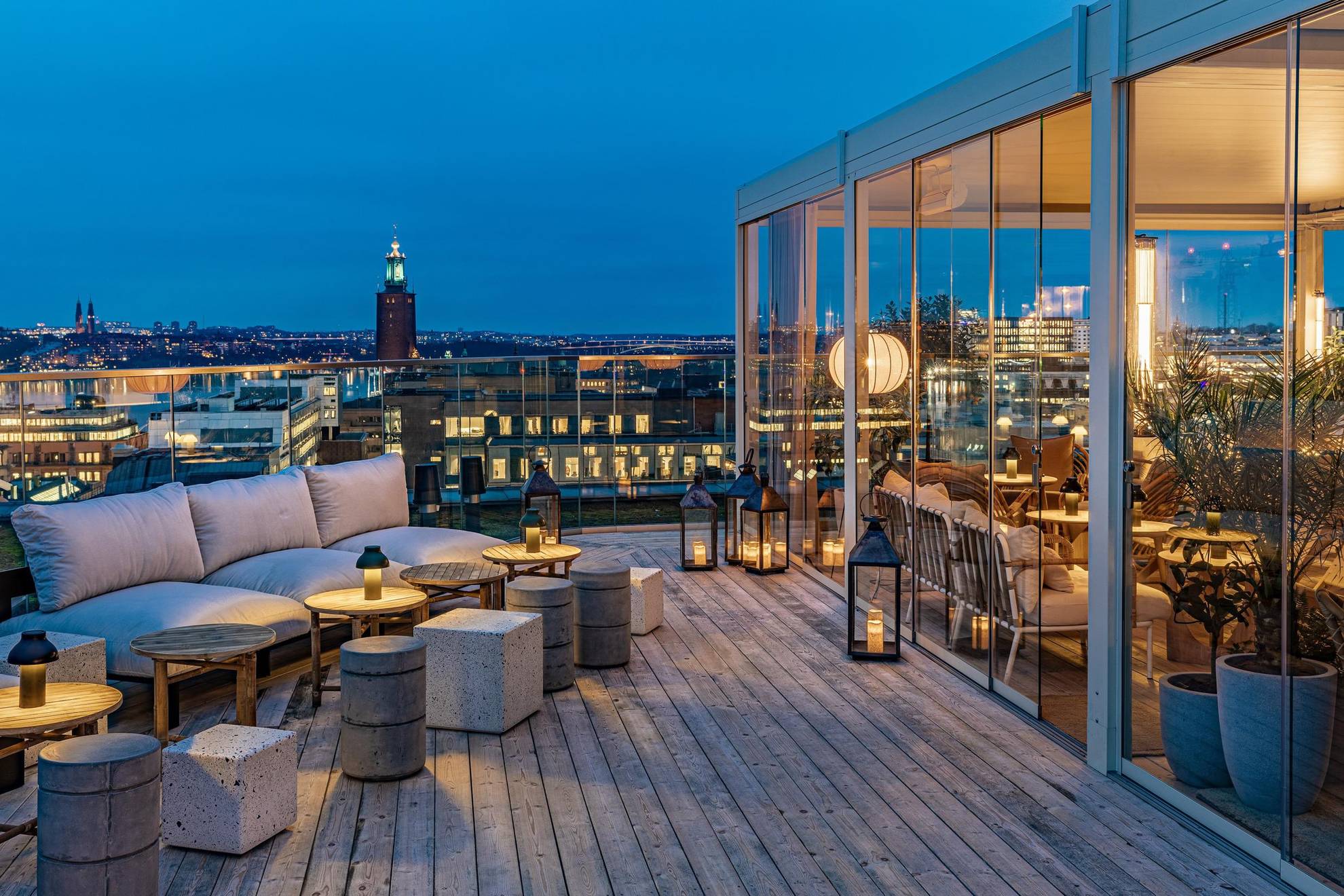 Un bar en plein air branché sur un rooftop avec une vue sur Stockholm et l'Hôtel de Ville. Sur la droite de la photo, on voit une véranda en verre.
