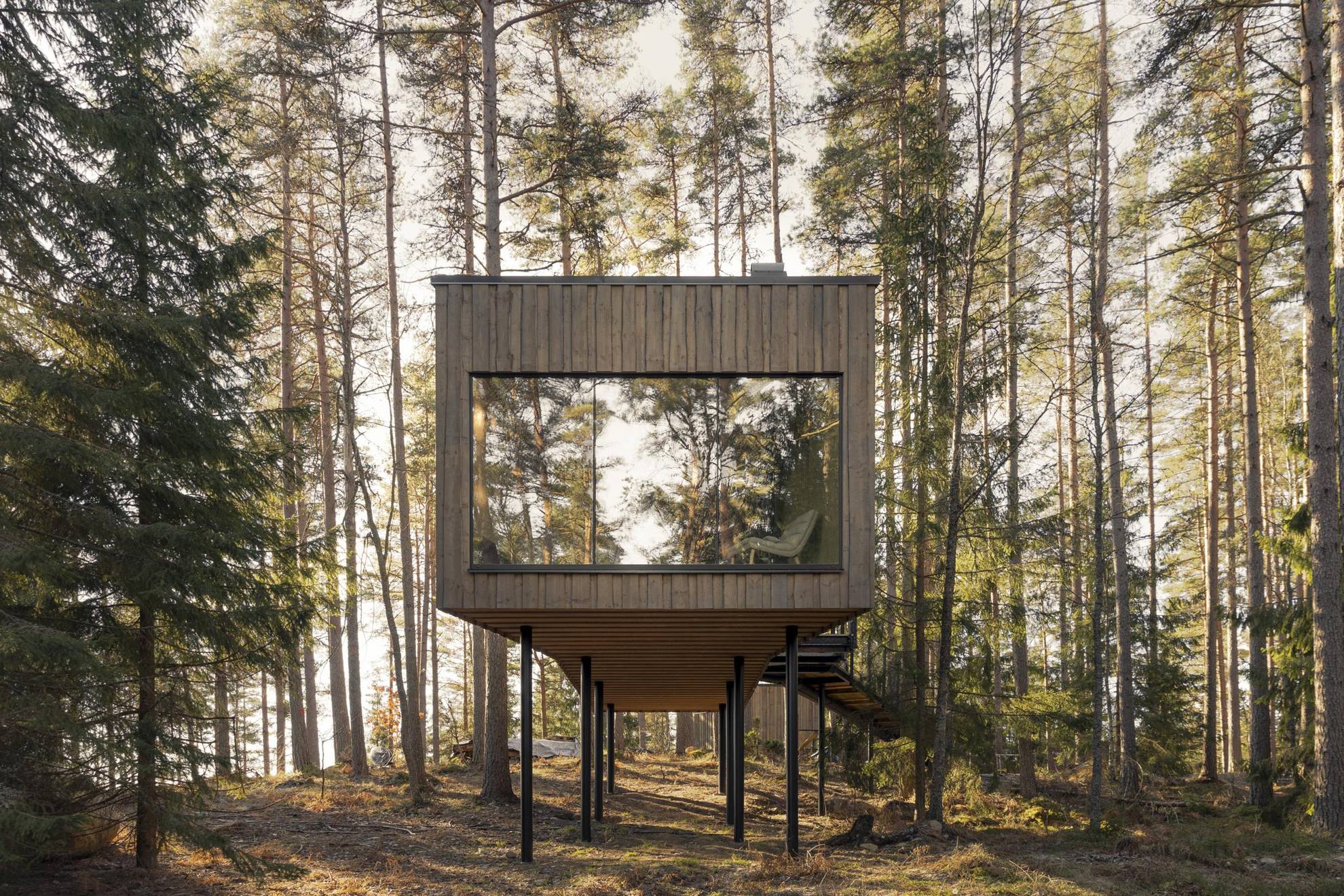 Une suite en bois rectangulare avec une énorme fenêtre est située dans la forêt.