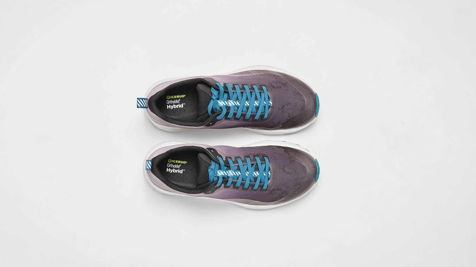 Des chaussures grises à lacets bleus sont posés sur une surface blanche.