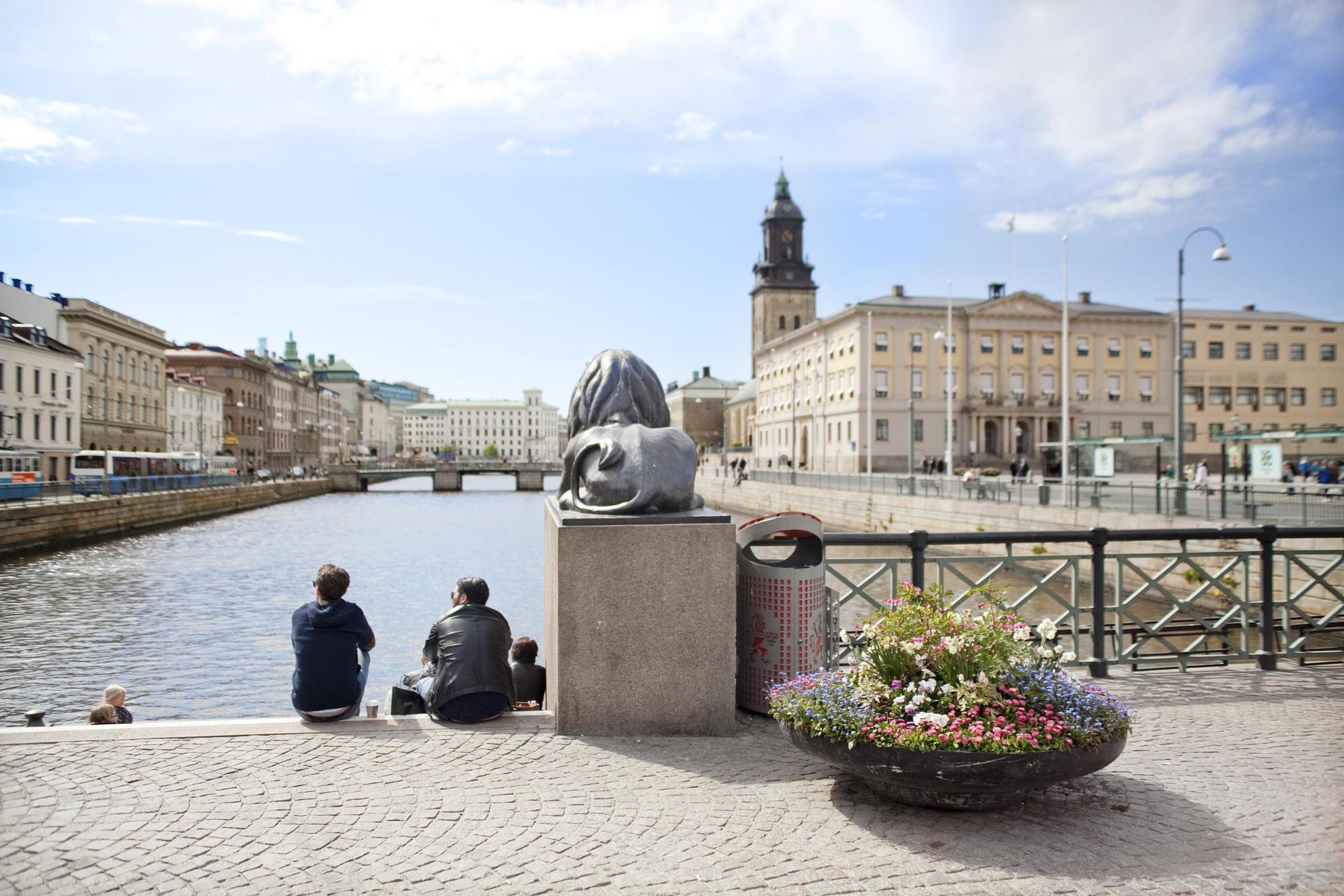 Deux personnes sont assises sur Lejontrappan à Brunnsparken. En arrière-plan, on voit l'hôtel de ville de Göteborg.