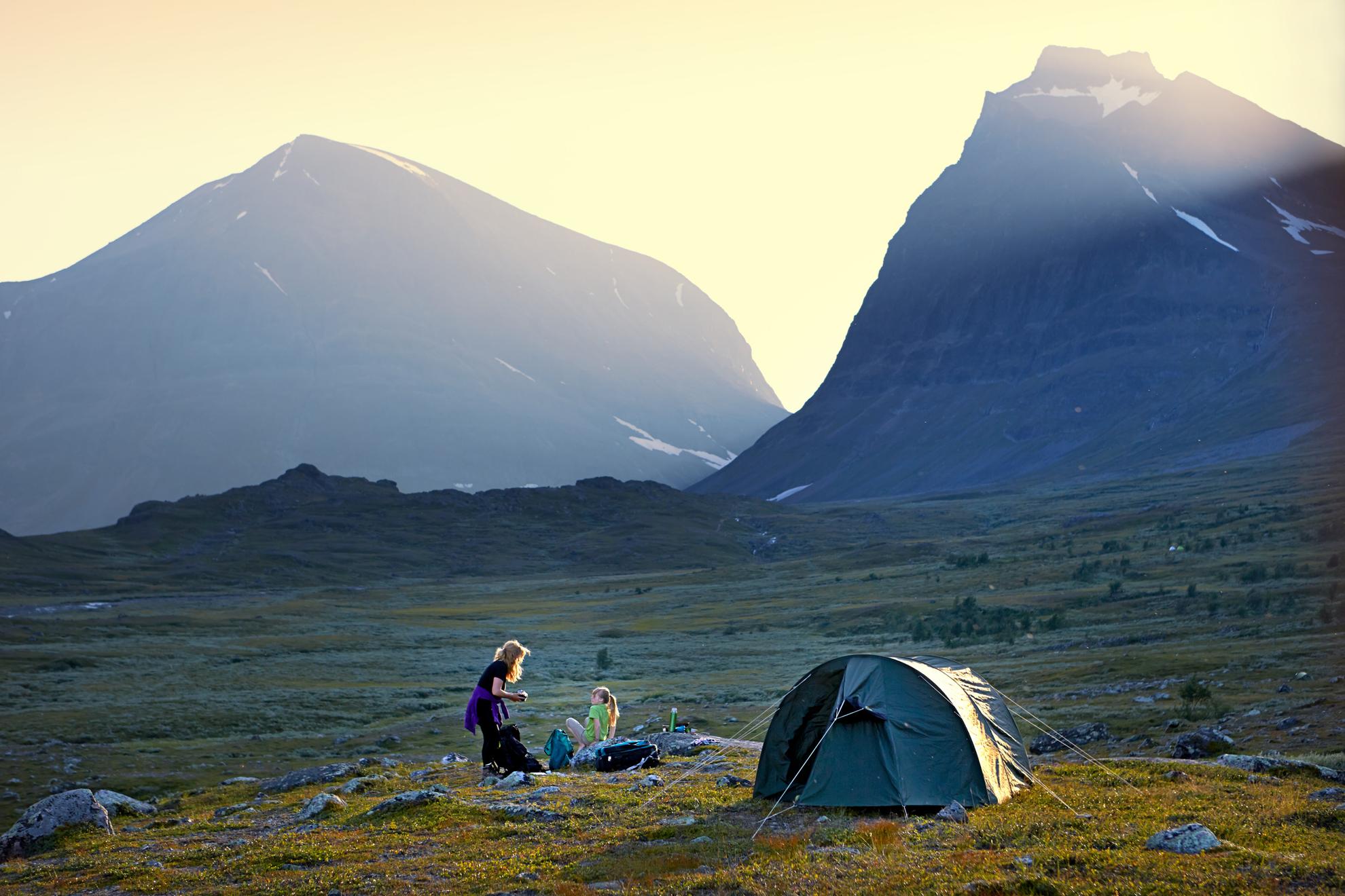 Deux filles campant dans la nature avec des montagnes en arrière-plan.
