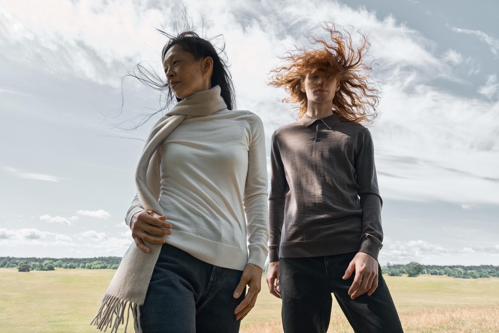 Une séance photo de mode avec deux femmes debout dans un champ, les cheveux au vent.