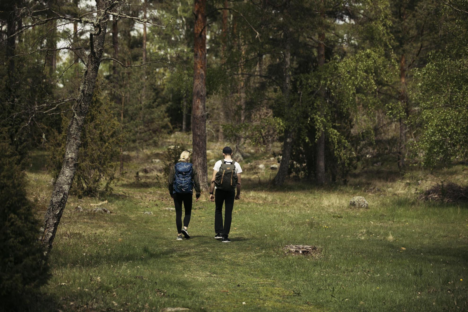 Deux personnes avec des sacs à dos randonnent à travers une forêt.